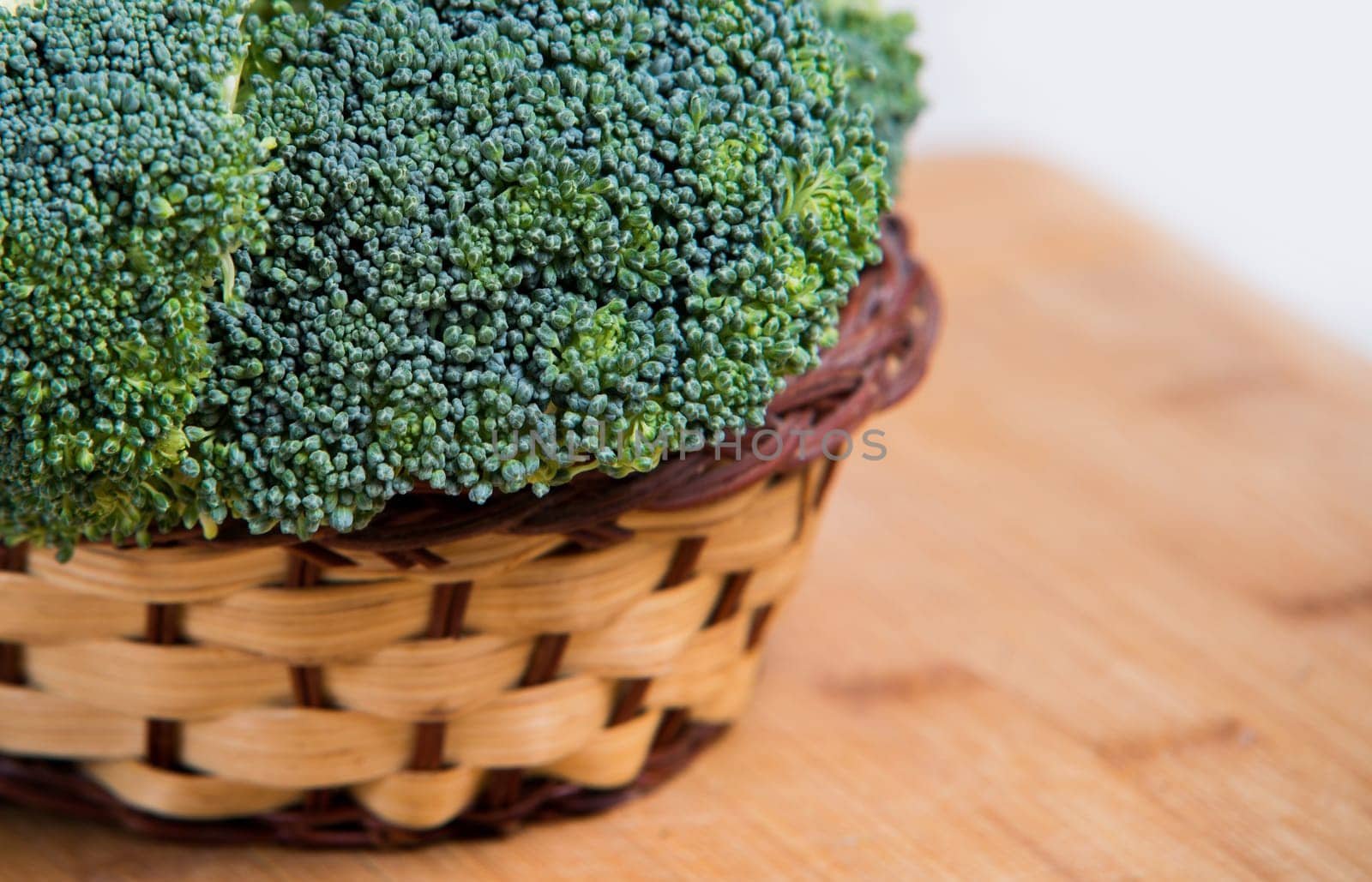 close up on fresh broccoli in basket solated on wood and white background