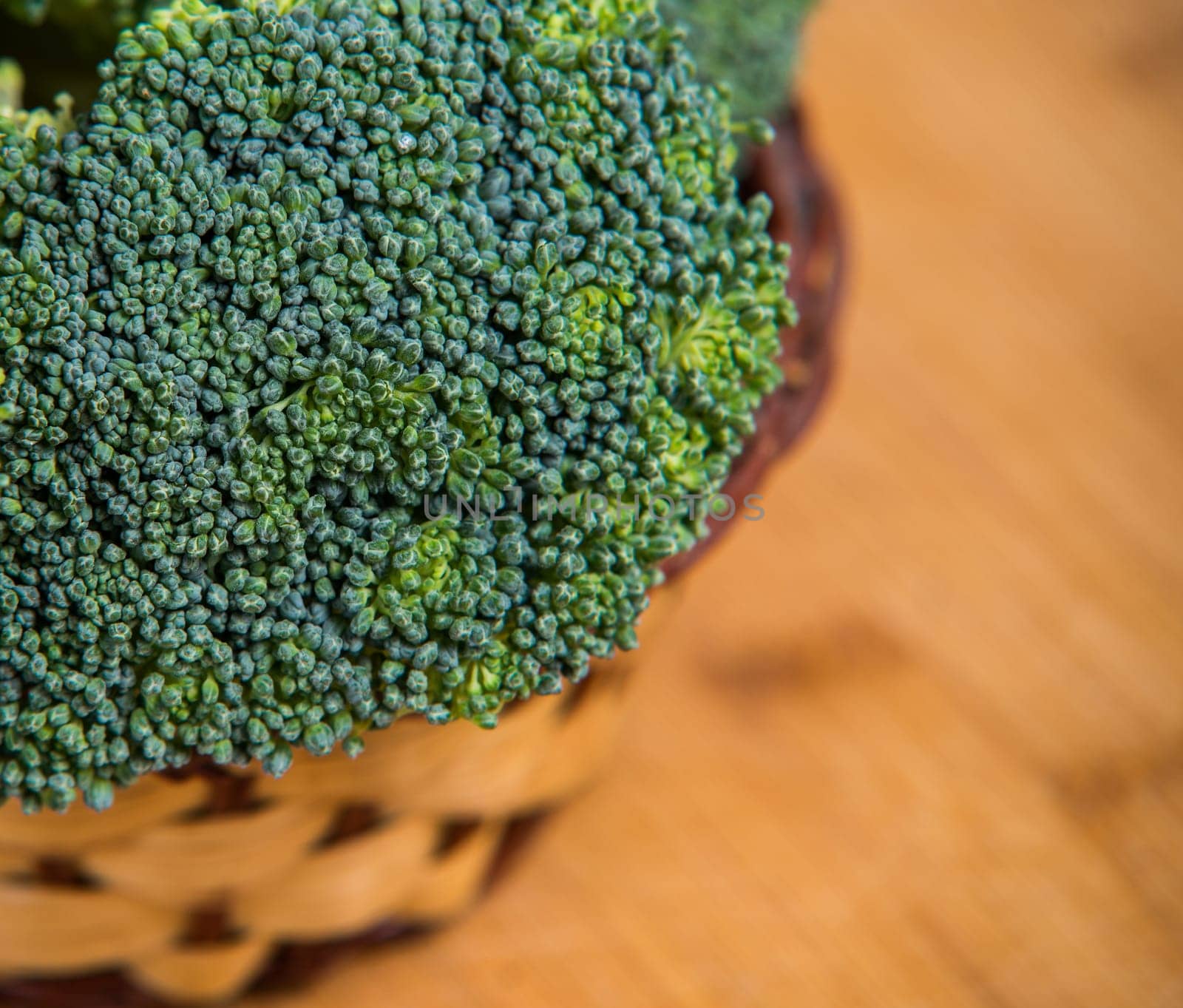 close up on fresh broccoli solated in basket on wooden background