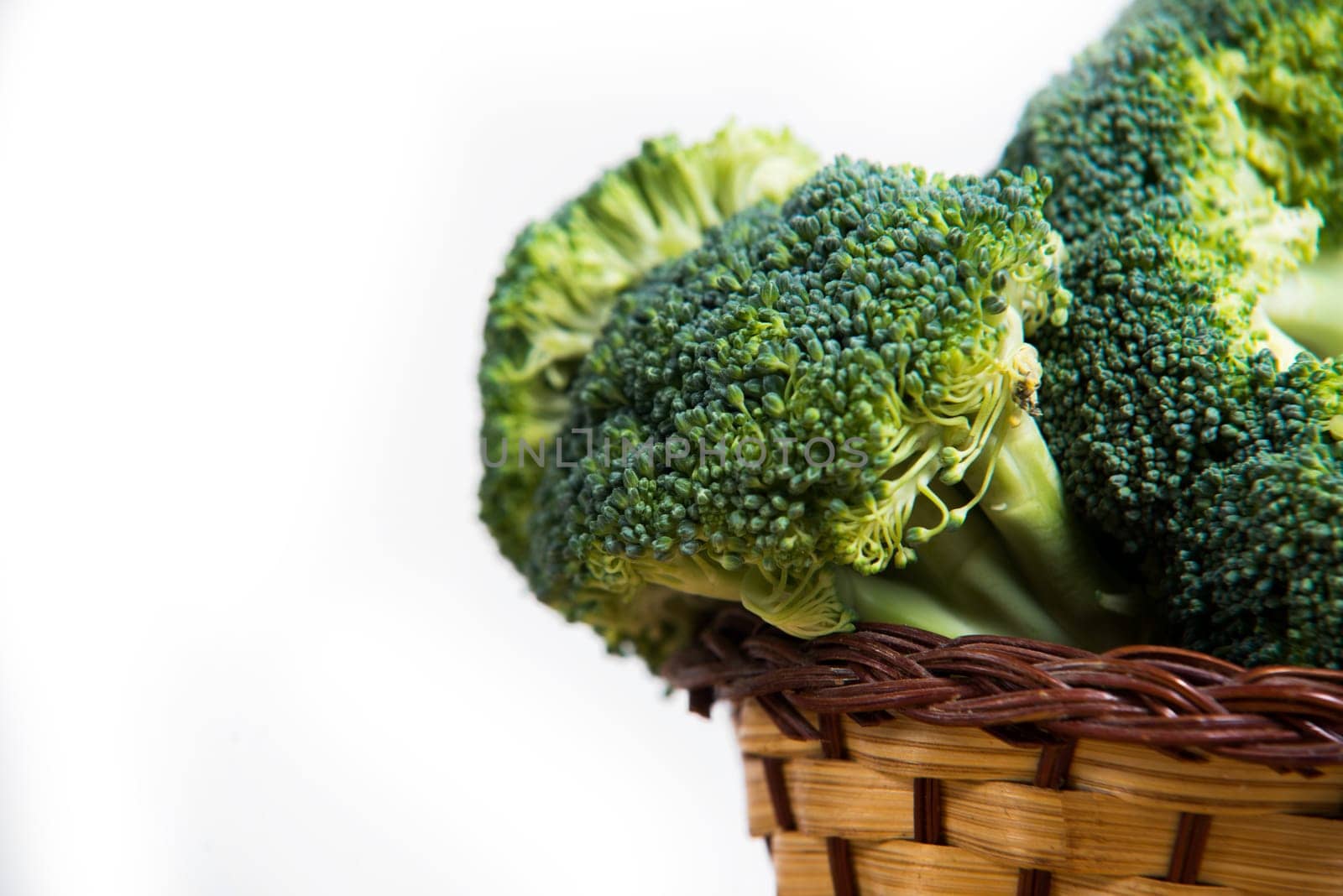 close up on fresh broccoli solated in basket on wood and white background