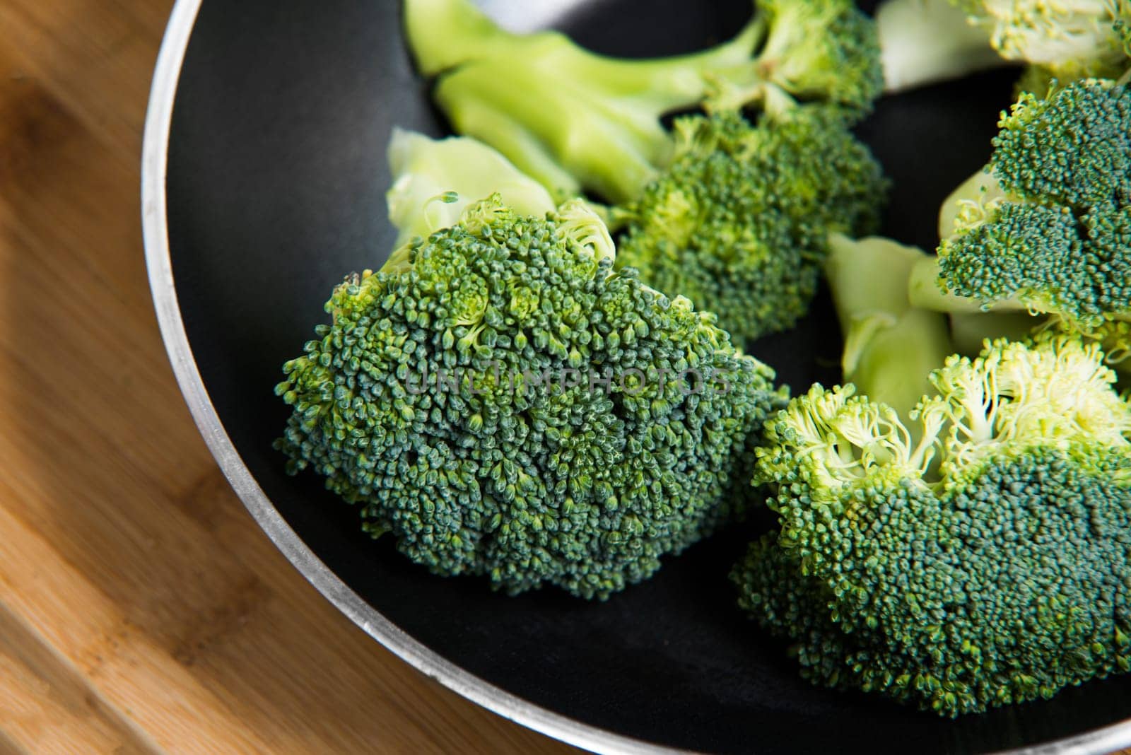 close up on fresh broccoli solated in pan on wooden background
