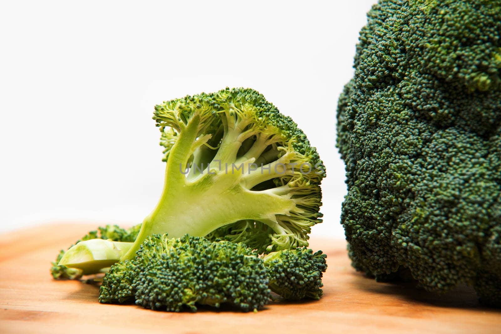 close up on fresh broccoli solated on wooden and white background