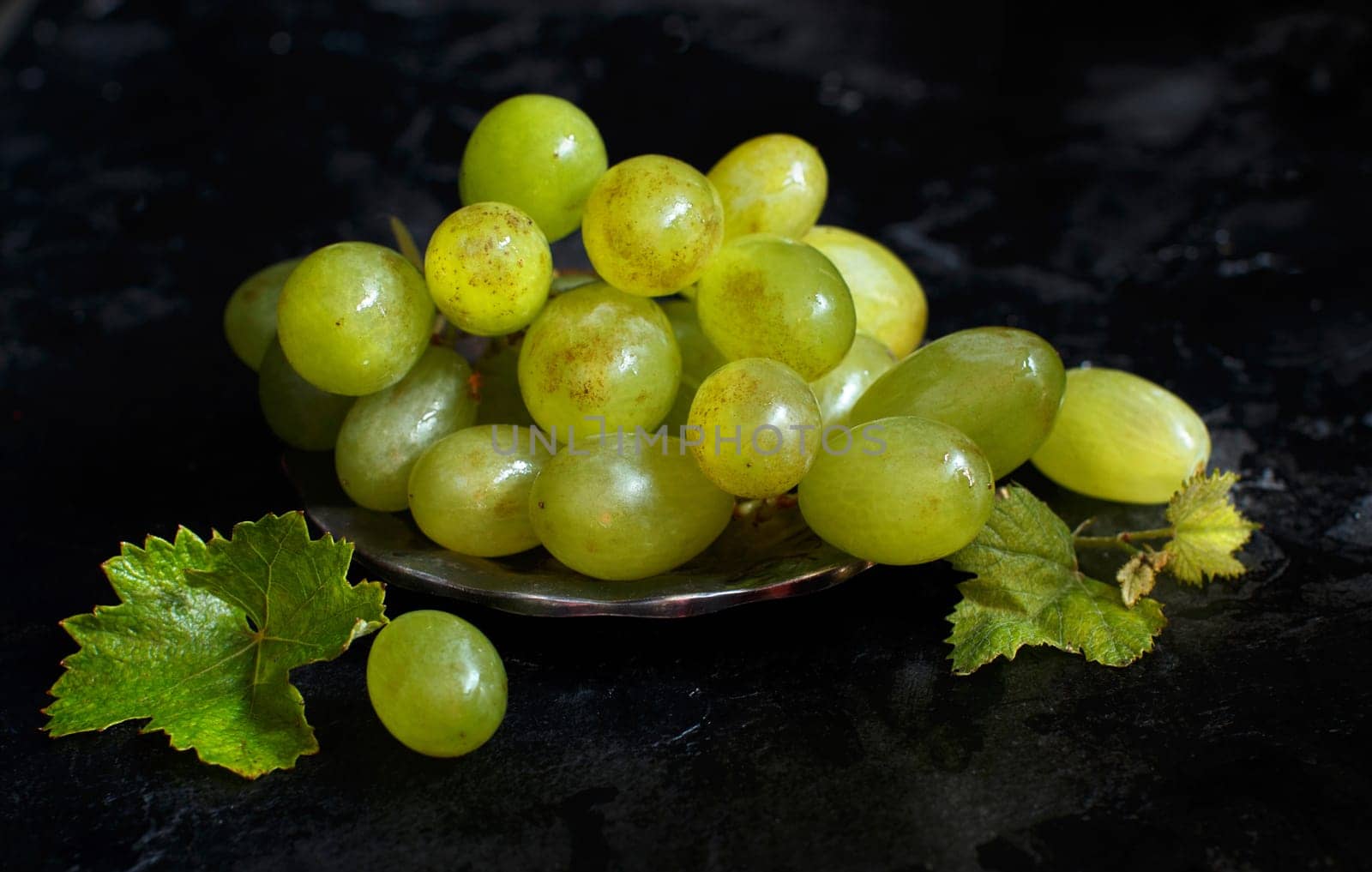 White grapes on a silver bowl on a dark Background