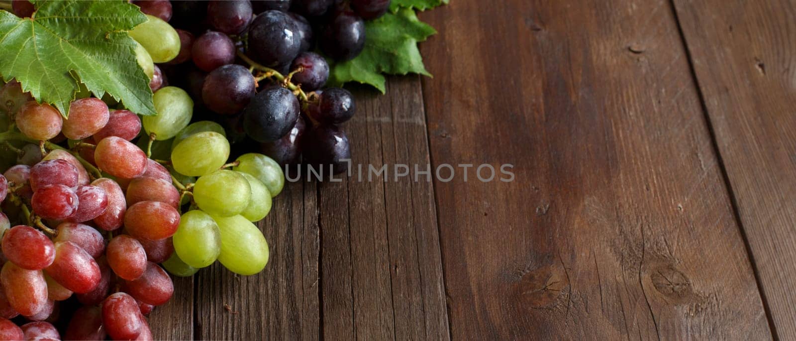 Grapes with leaves on a dark wooden table