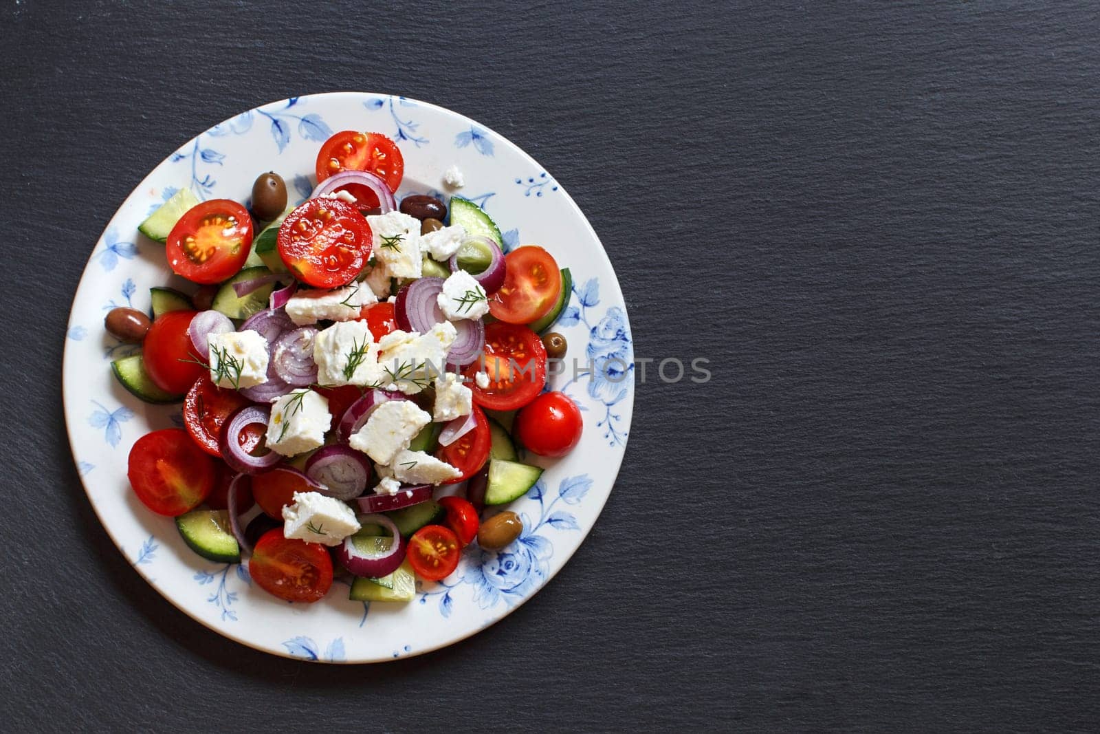 Greek salad with tomatoes, feta cheese, cucumbers, onions and olives