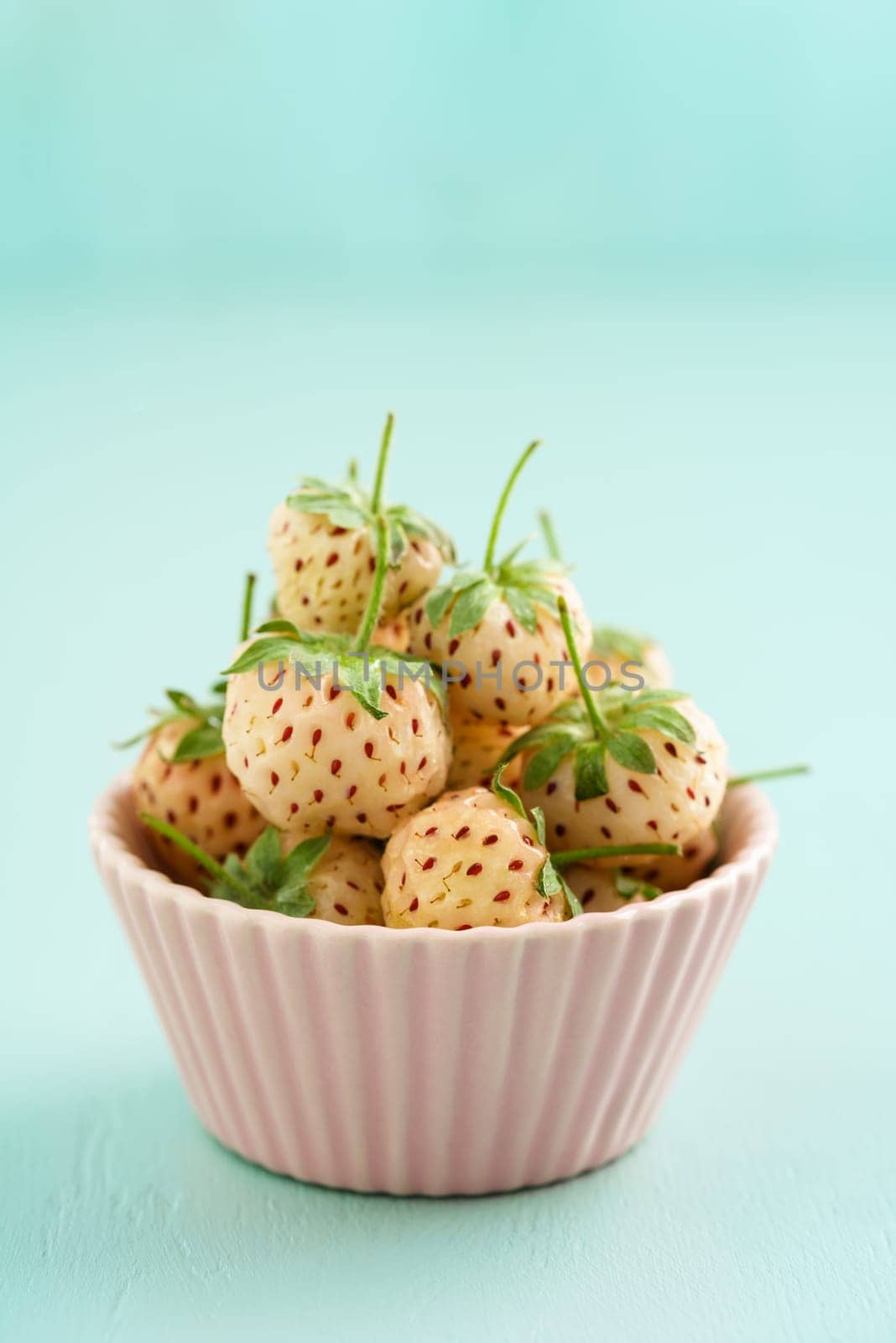 Fresh raw pineberries in a pink bowl