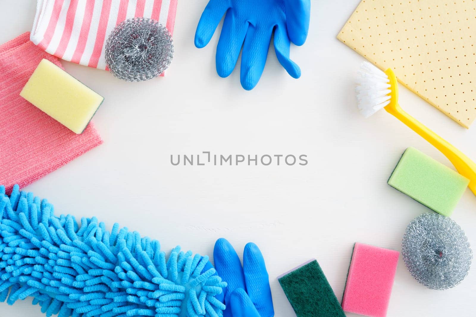 Collection of pastel-coloured cleaning supplies on white background with copyspace