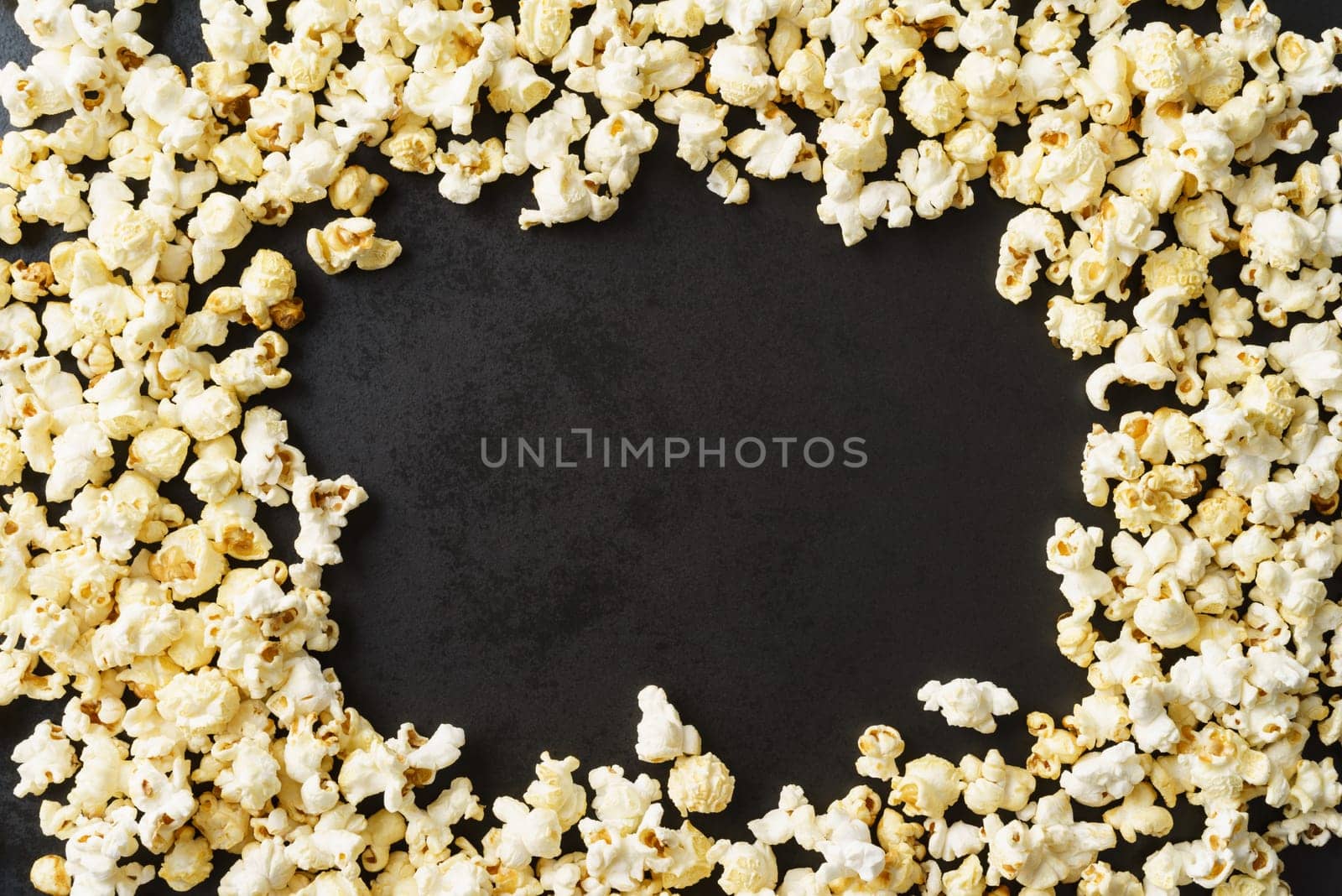 Frame of popcorn on dark textured background with copyspace