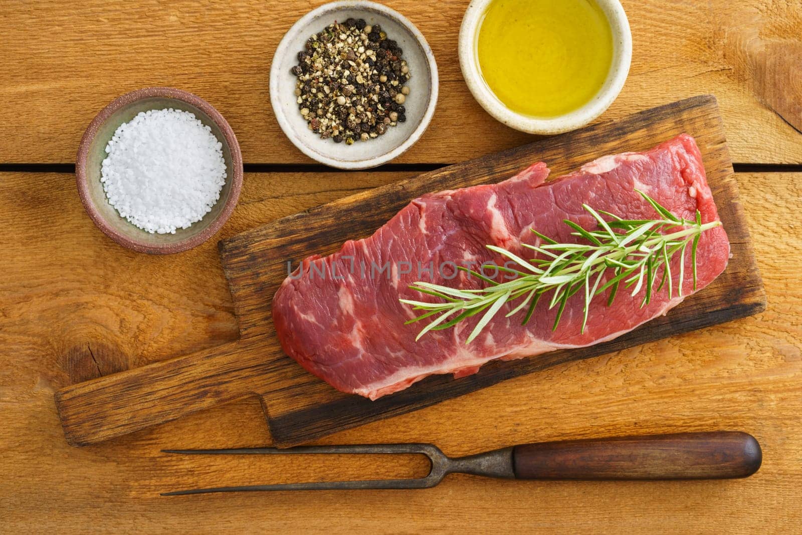 Uncooked rump steak on wooden board on wood