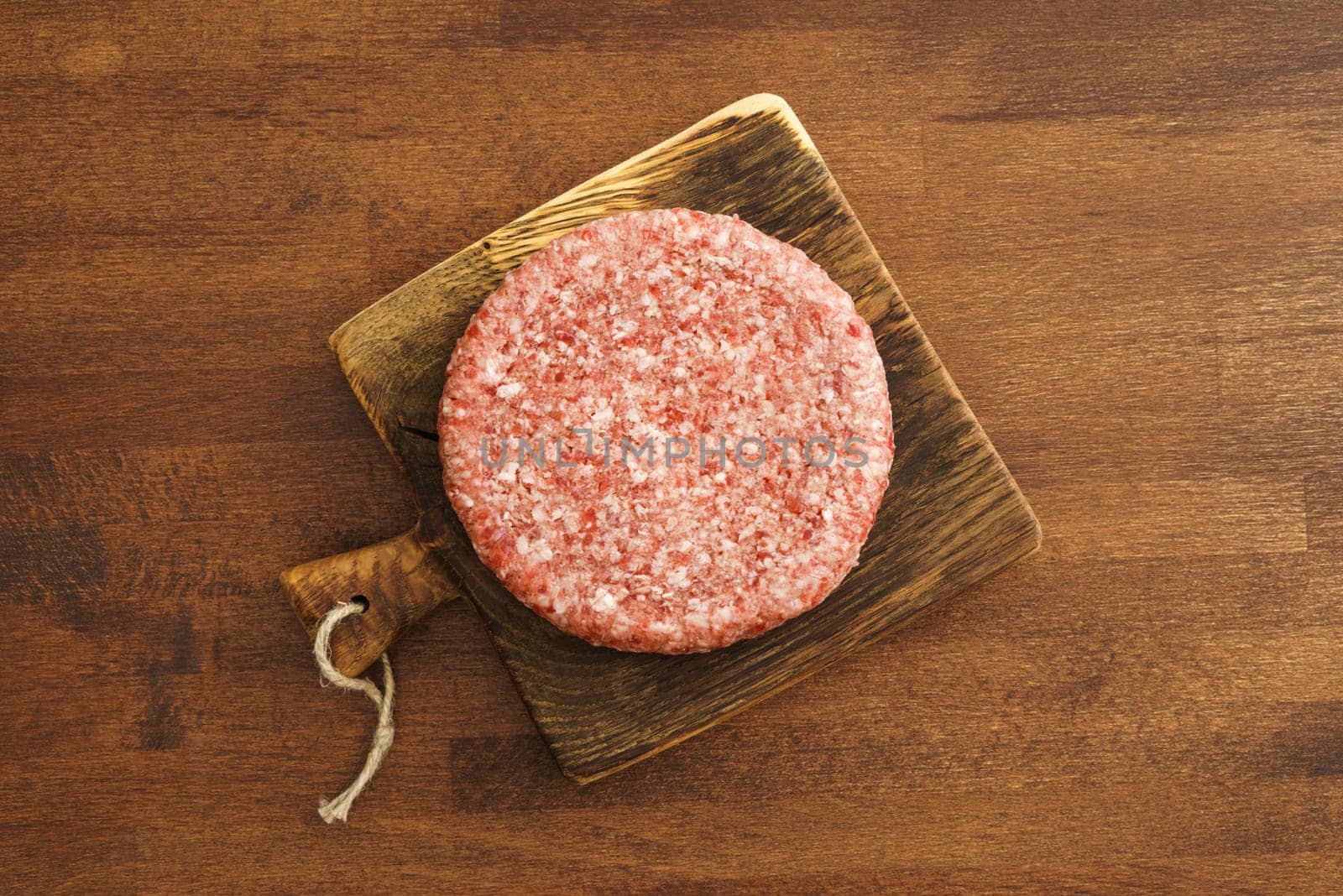 Burger patty from ground beef on wooden board