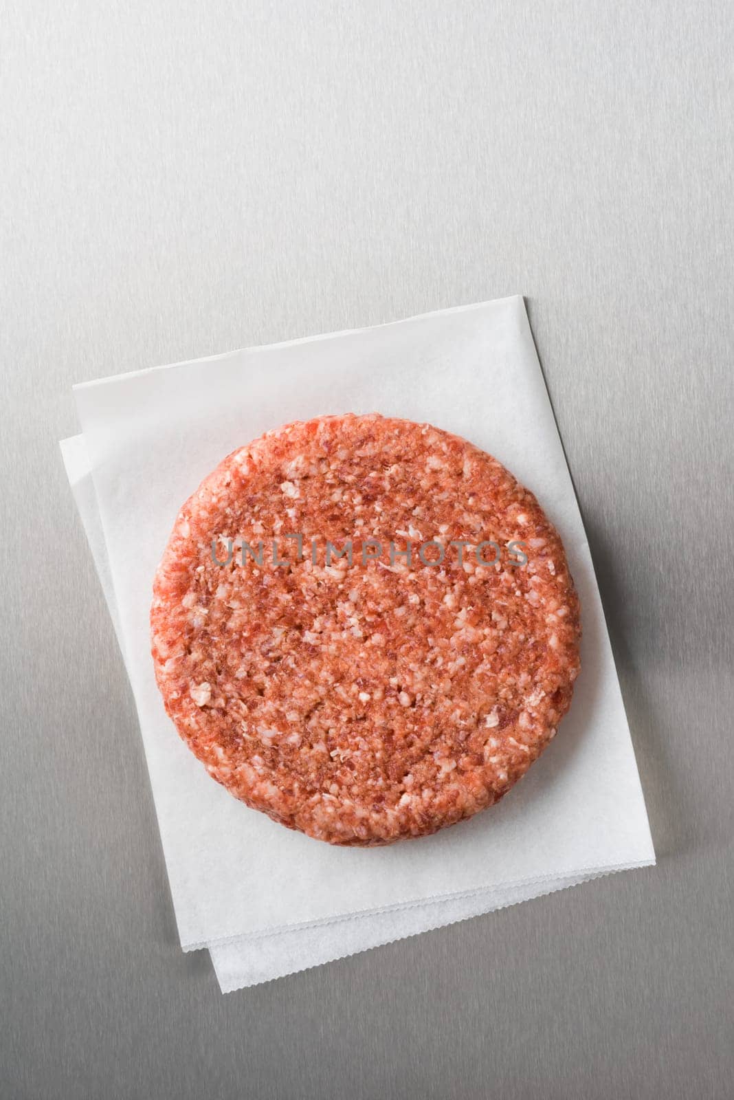 Burger patty from ground beef on parchment paper on stainless steel