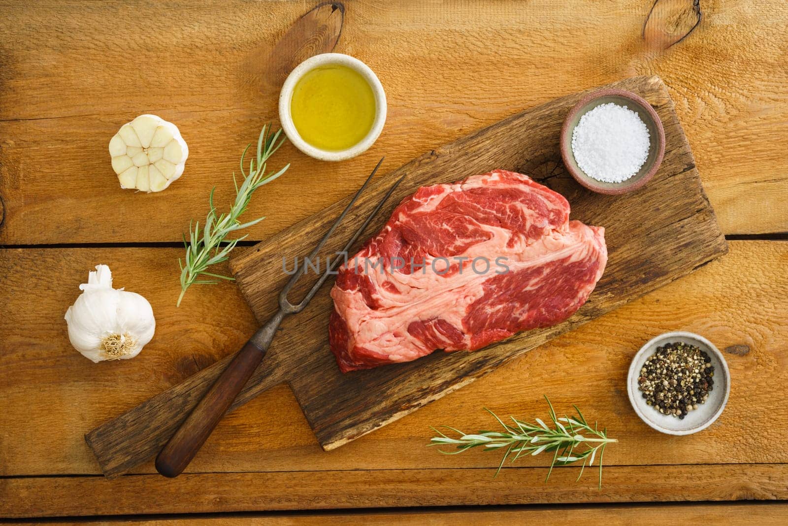 Uncooked chuck eye steak on wooden board on wood