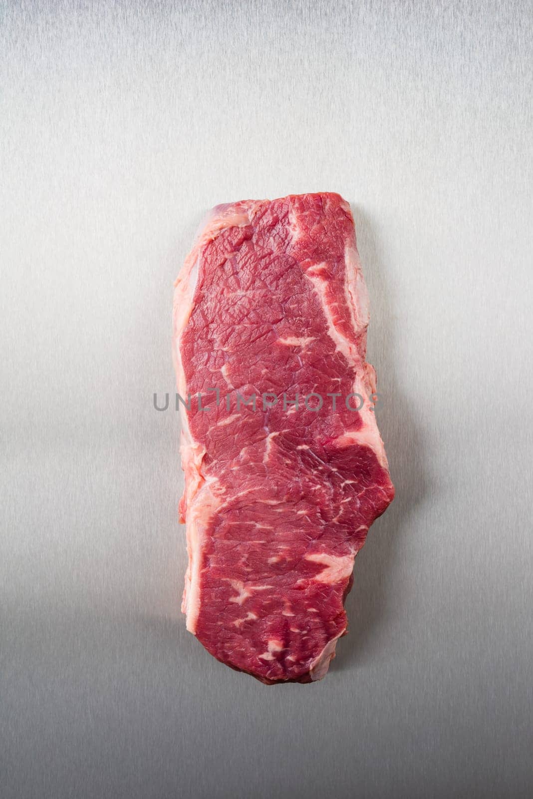 Uncooked rump steak on stainless steel from above