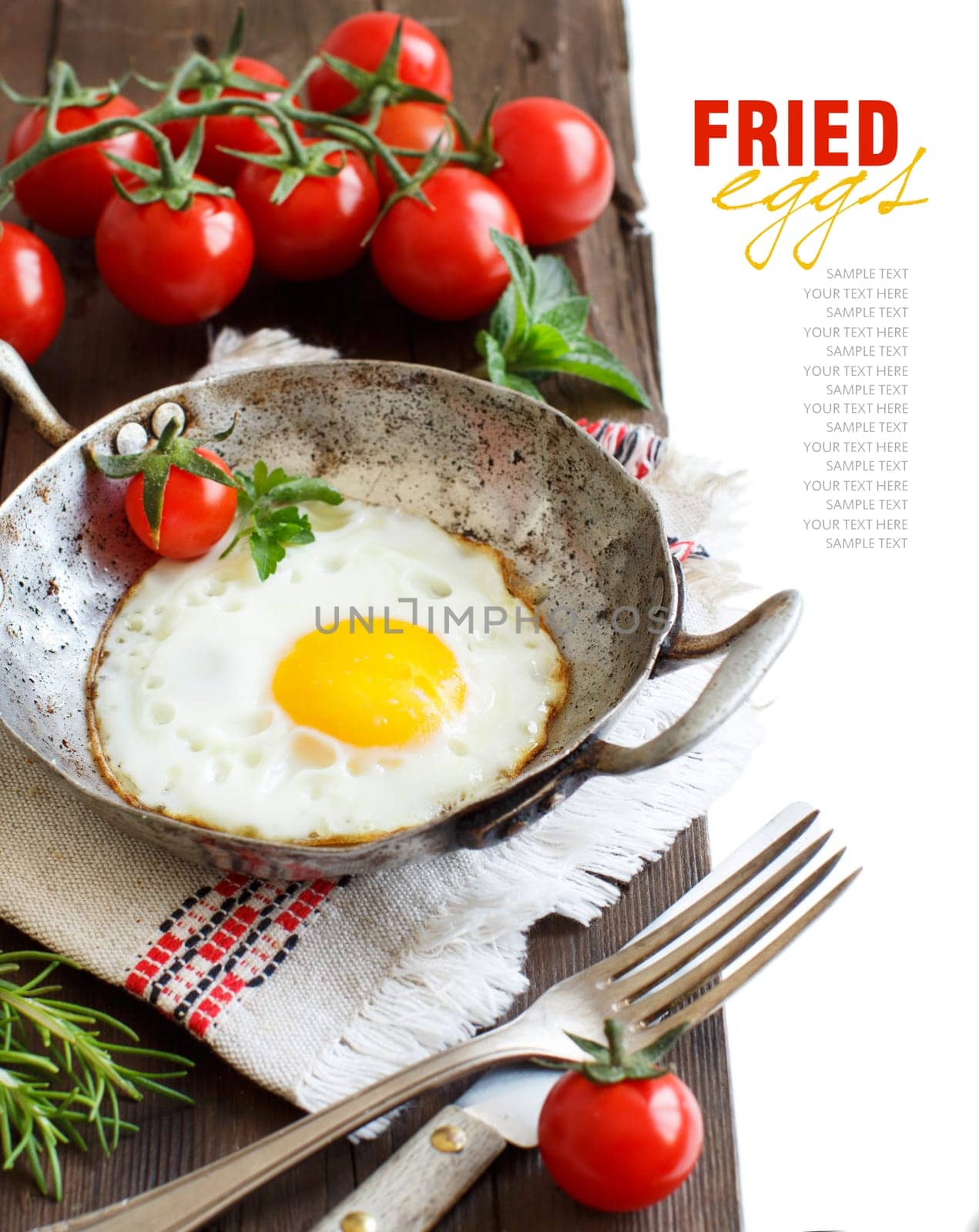 Fried egg with tomatoes, homemade bread and herbs on a old frying pan on wood
