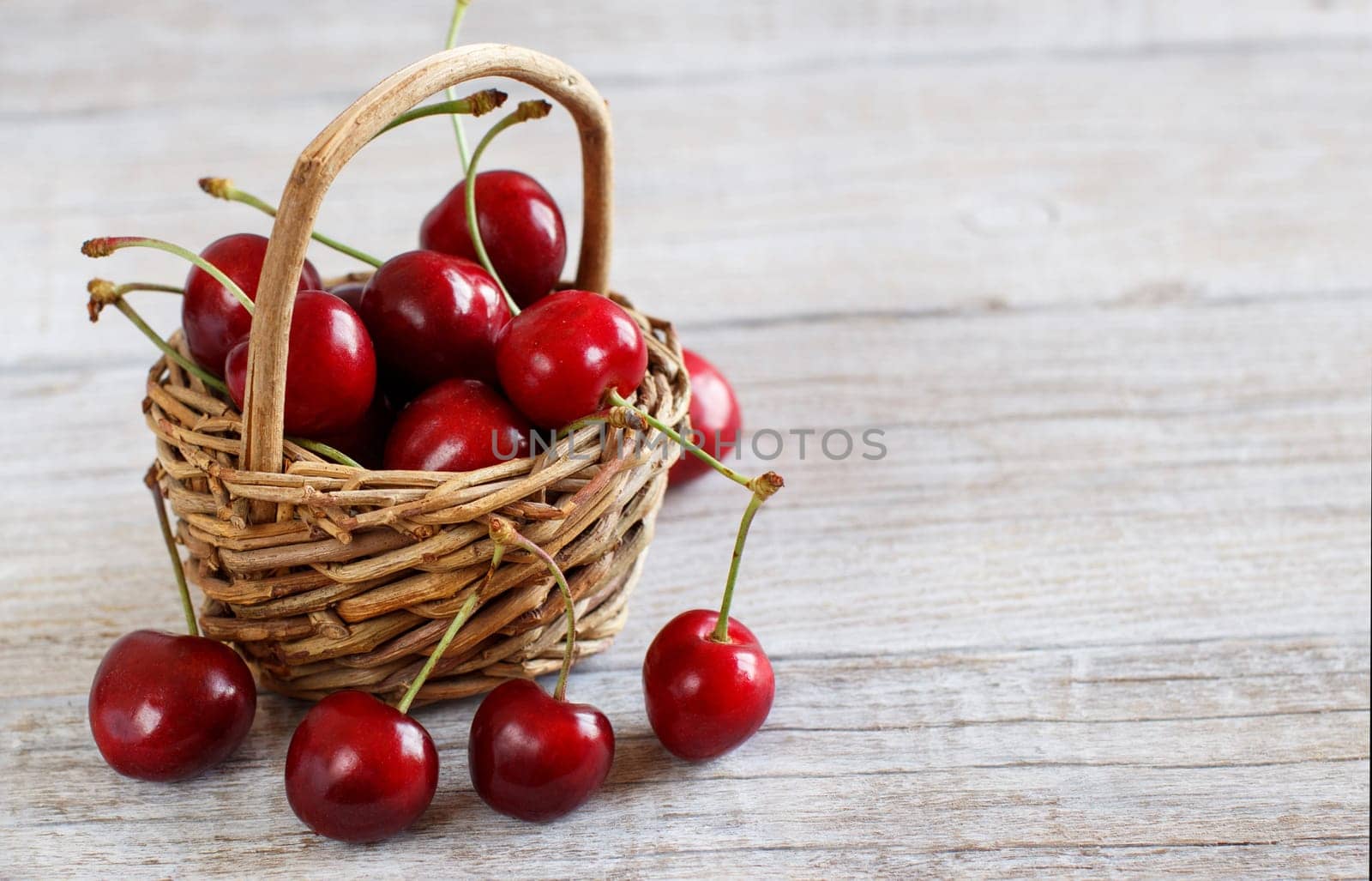 Red cherries in a basket on a wooden background