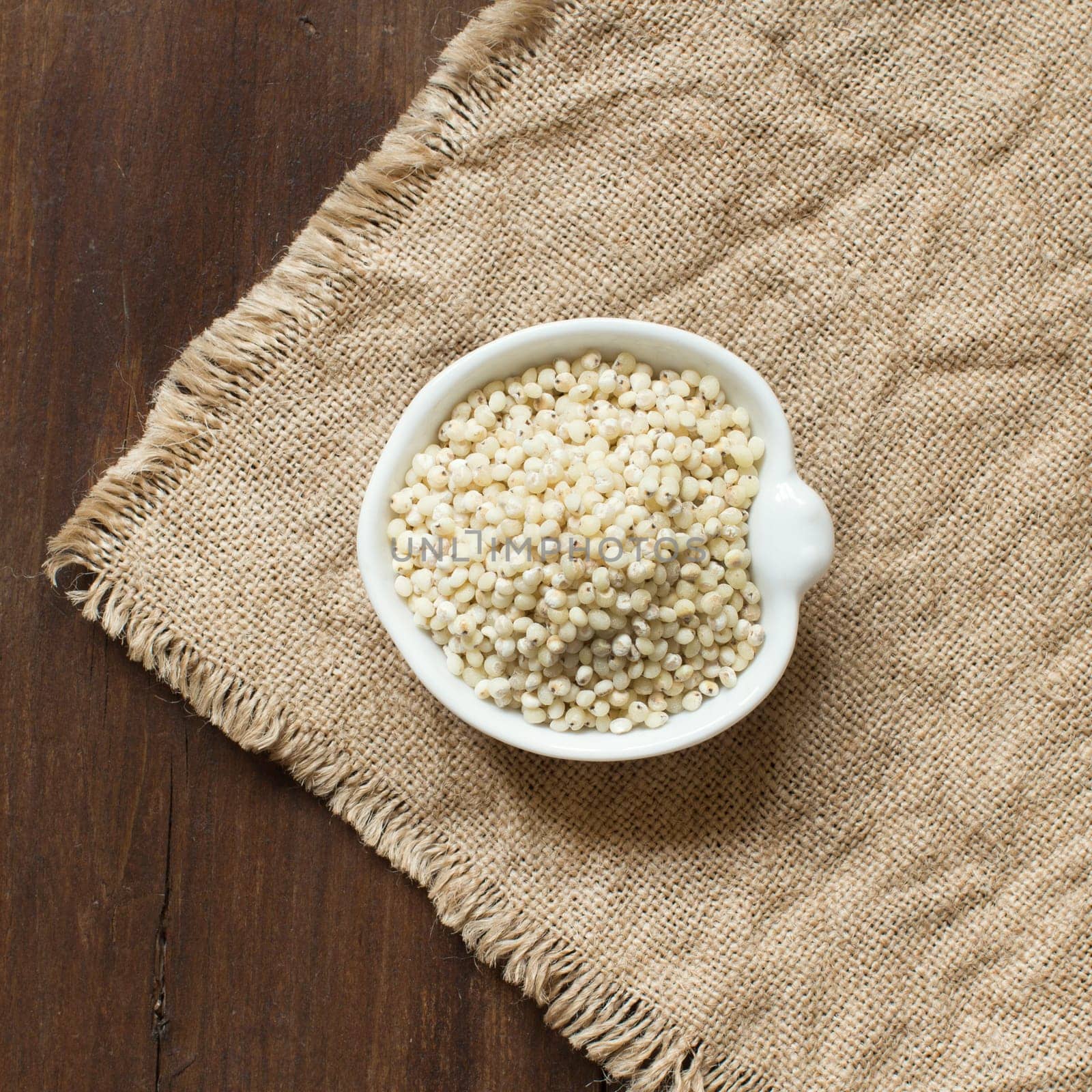 White Sorghum grain in a bowl on burlap background