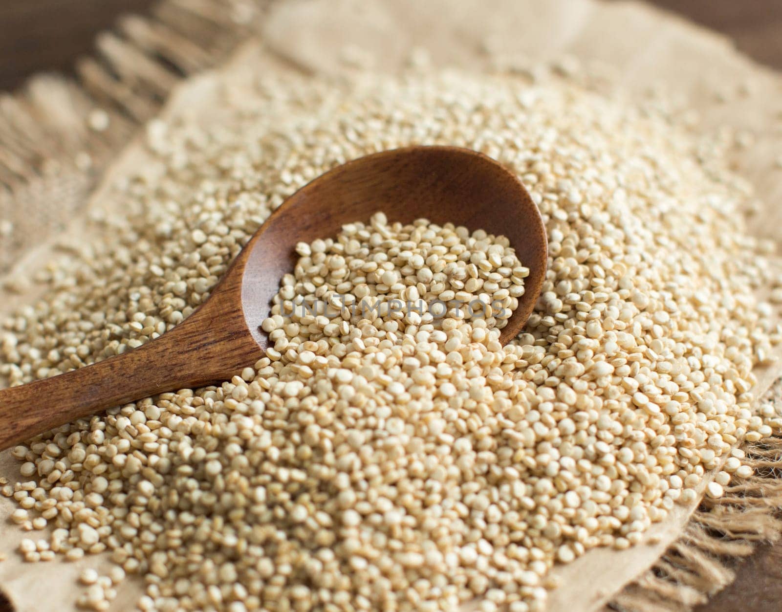 Pile of White Quinoa with a spoon on a wooden table