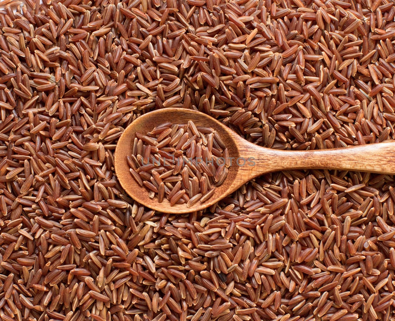 Red rice with a wooden spoon close up