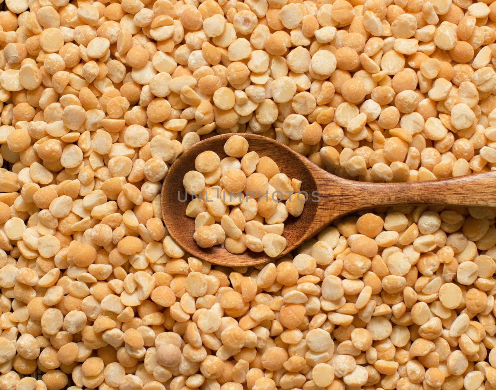 Uncooked Yellow split peas with a spoon close up