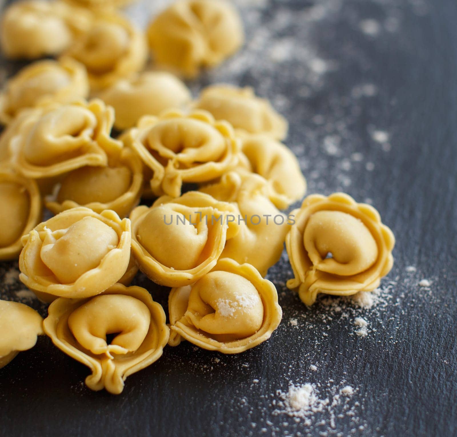 Homemade raw Italian tortellini on a dark background