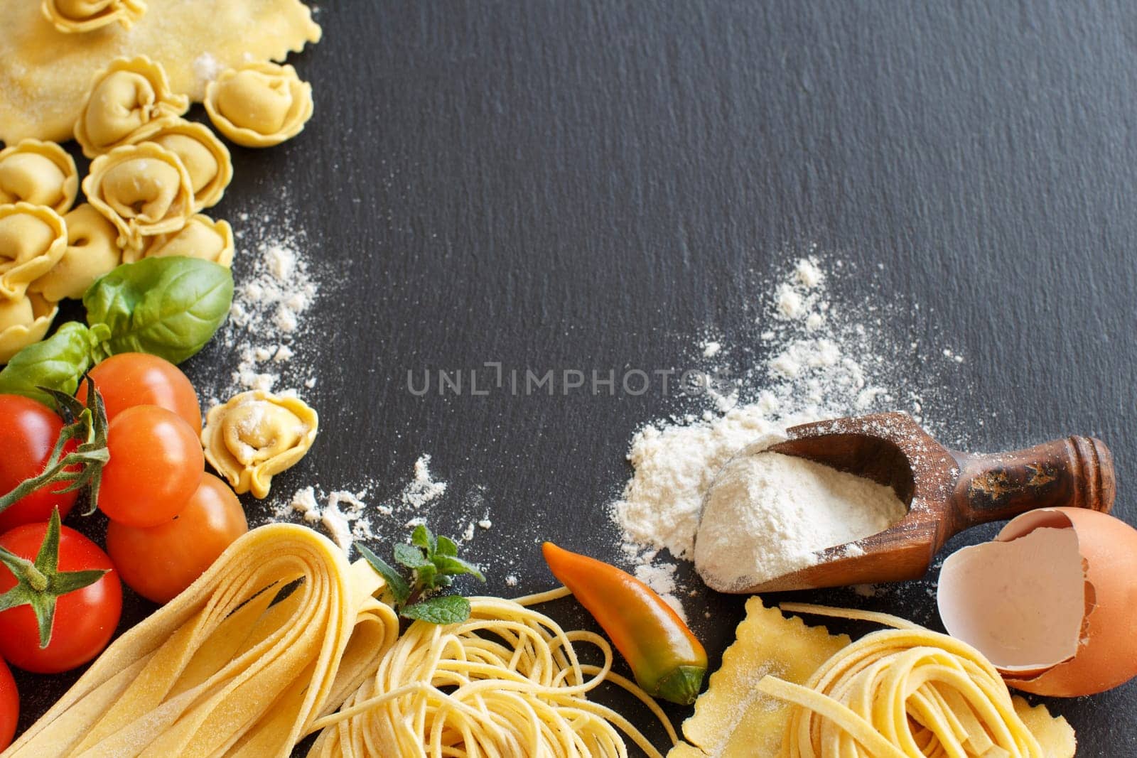 Fresh pasta and ingredients on a dark board