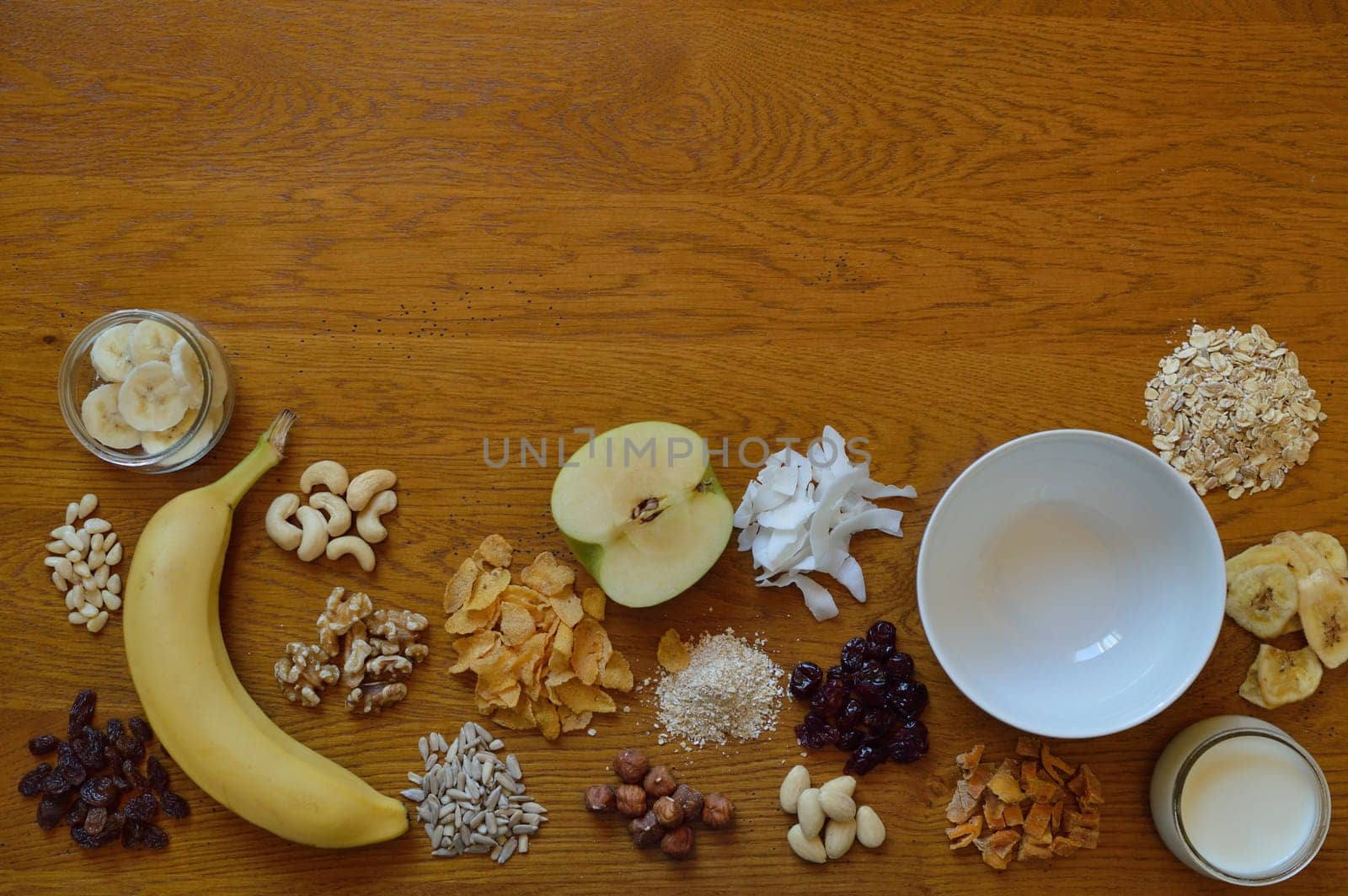 Muesli bowl on breakfast table with individual components of a muesli around it