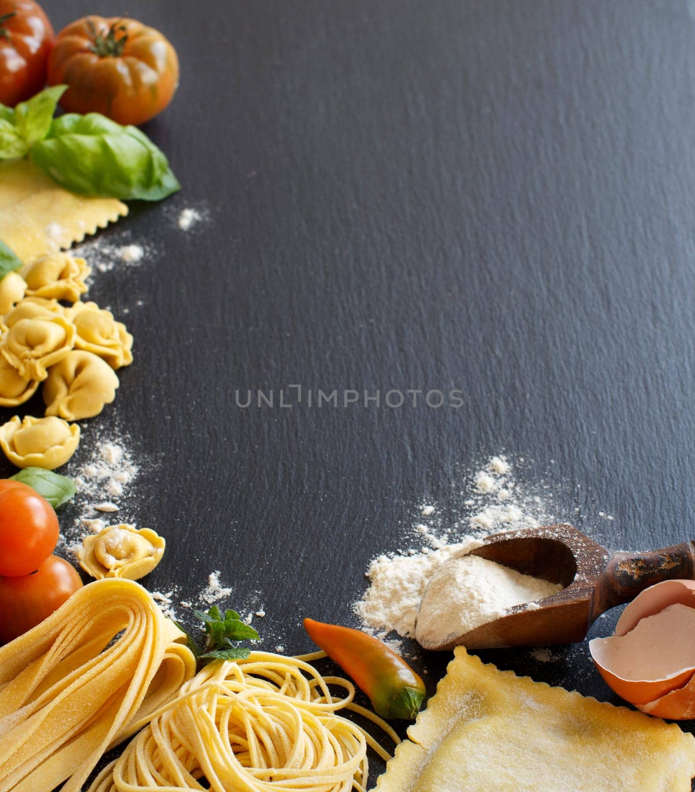 Fresh pasta and ingredients on a dark board
