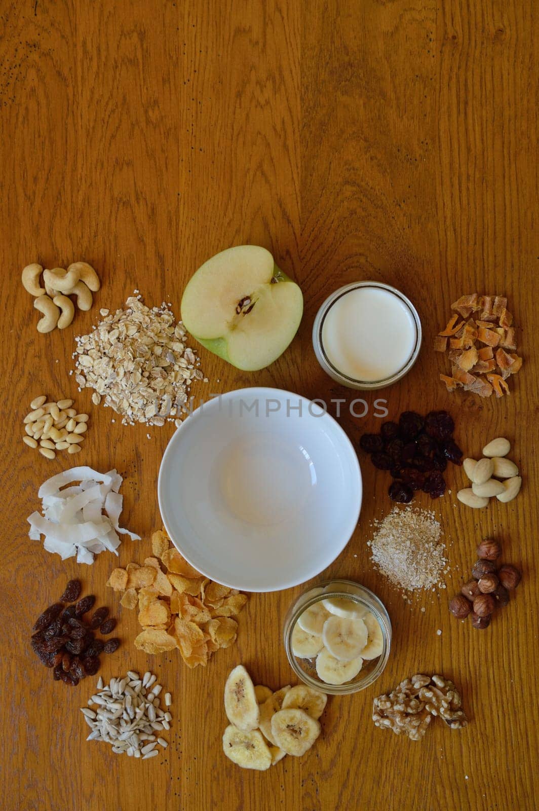 Muesli bowl on breakfast table with individual components of a muesli around it