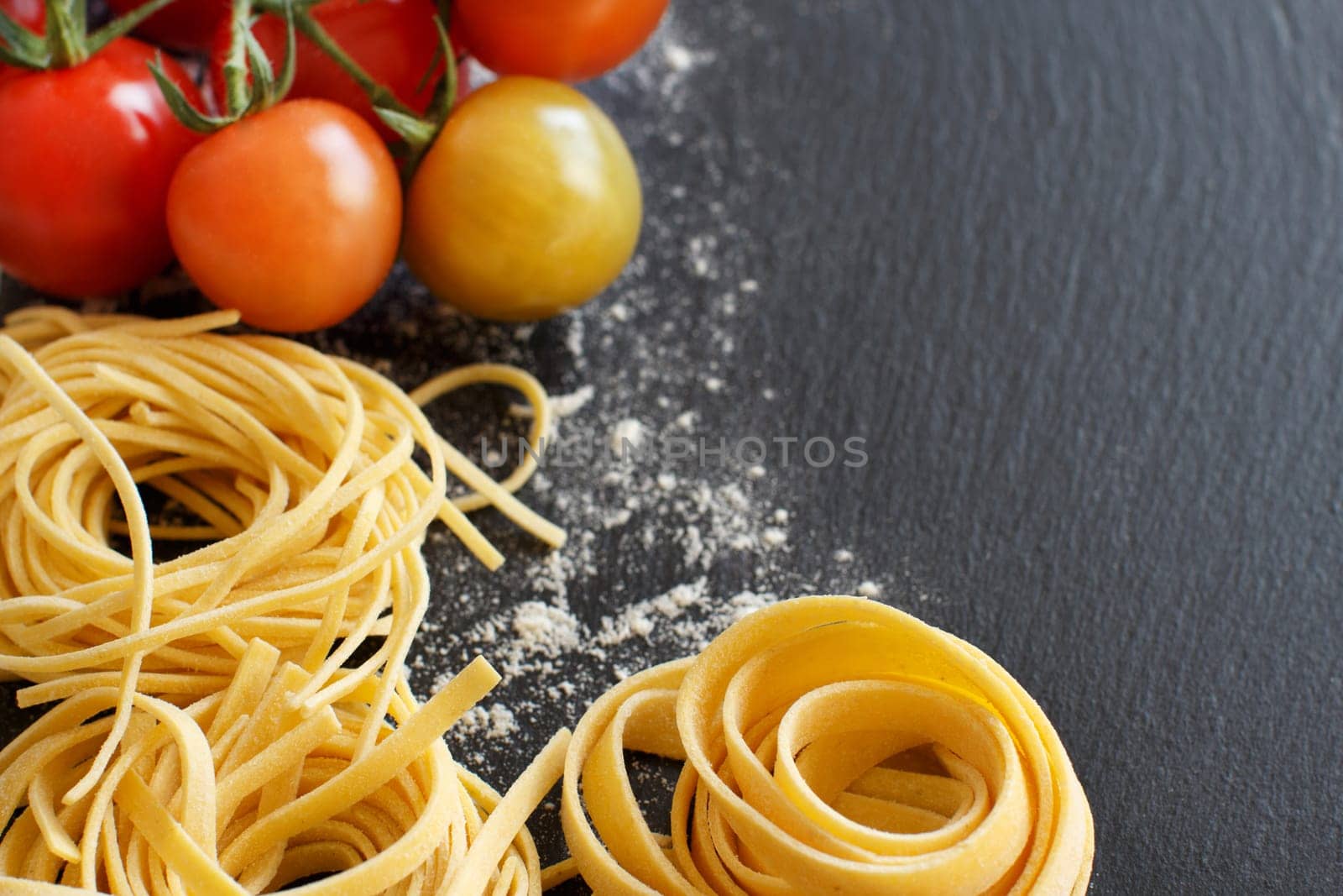 Fresh pasta and tomatoes on a dark board