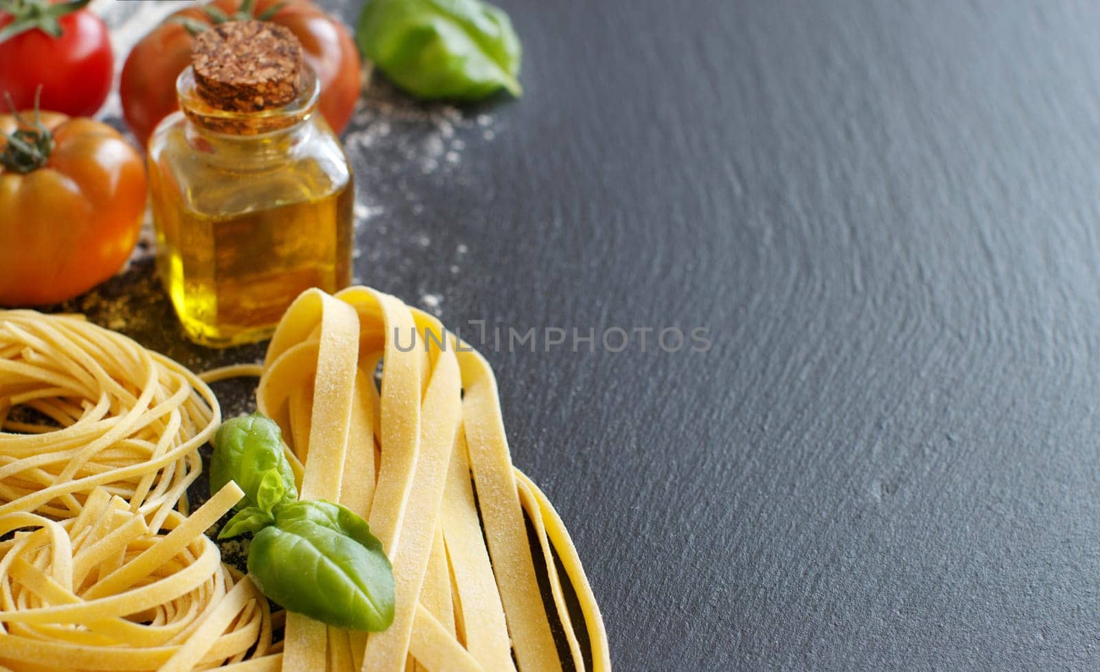 Fresh pasta and ingredients on a dark board