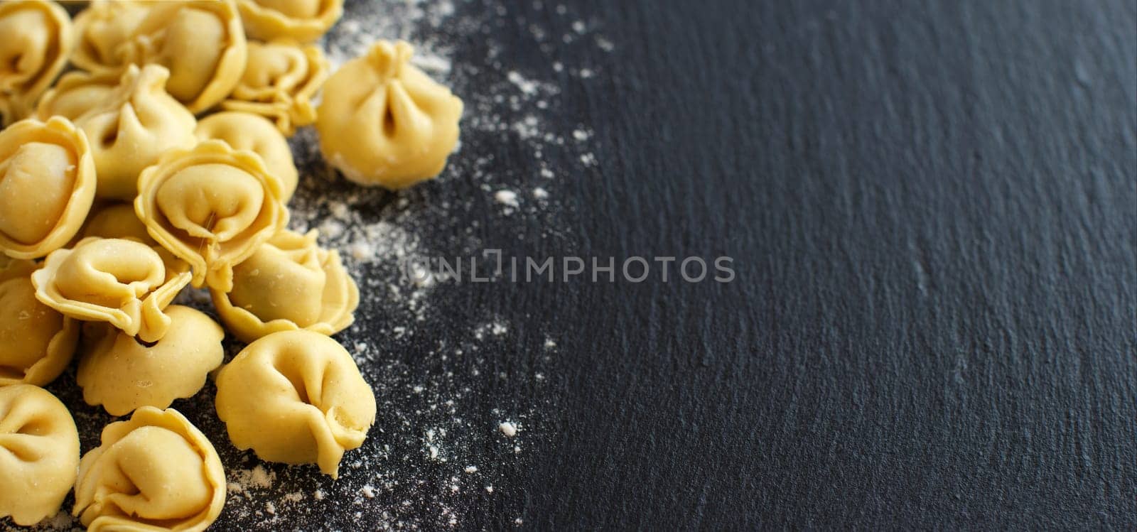 Homemade raw Italian tortellini on a dark background