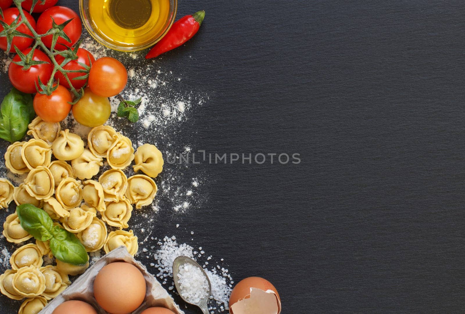 Fresh pasta and ingredients on a dark board