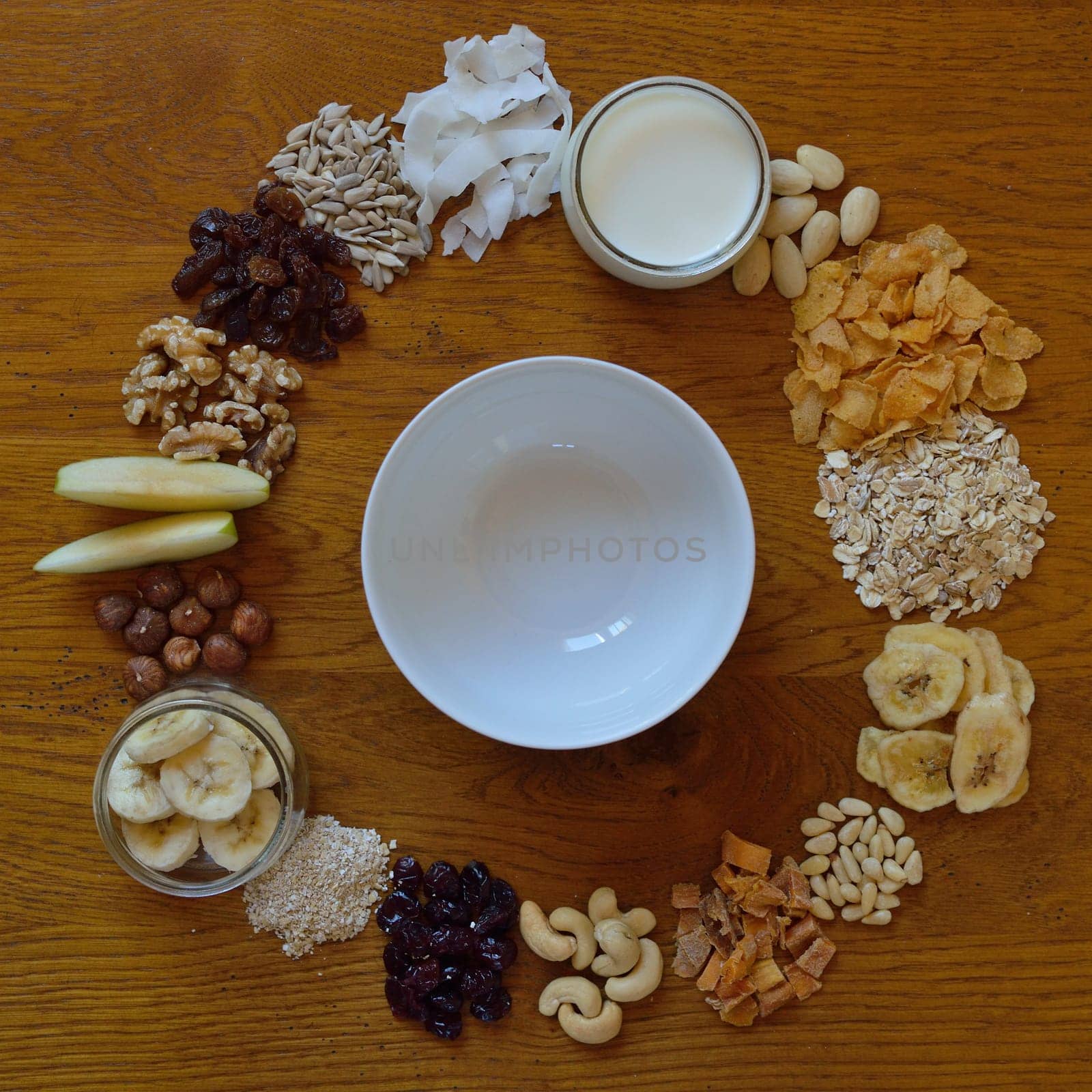 Muesli bowl on breakfast table with individual components of a muesli around it