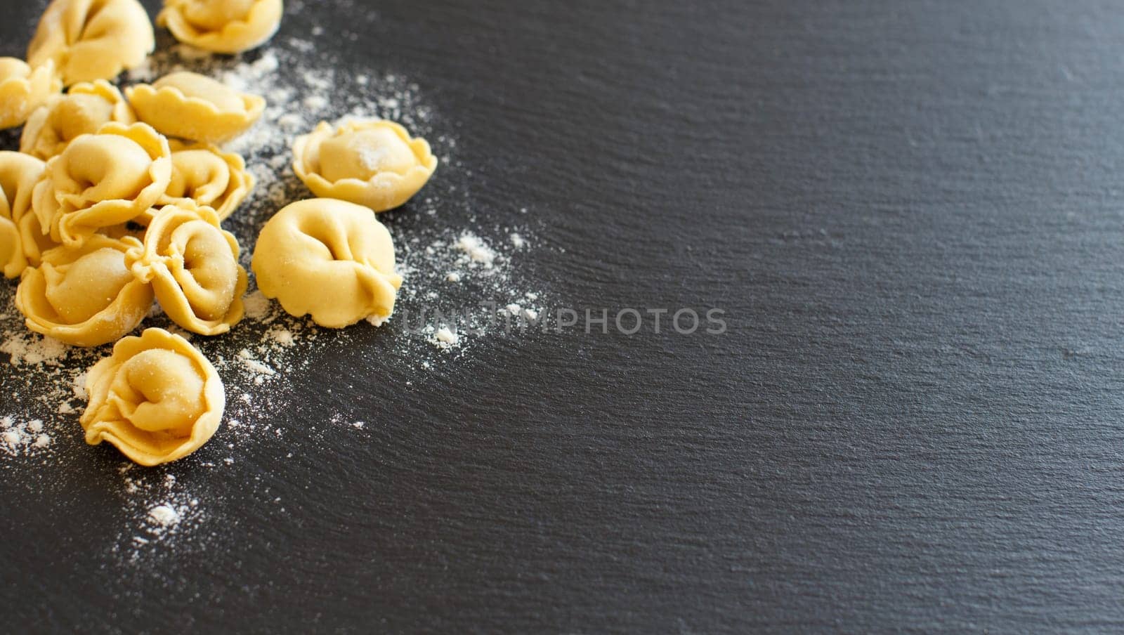 Homemade raw Italian tortellini on a dark background