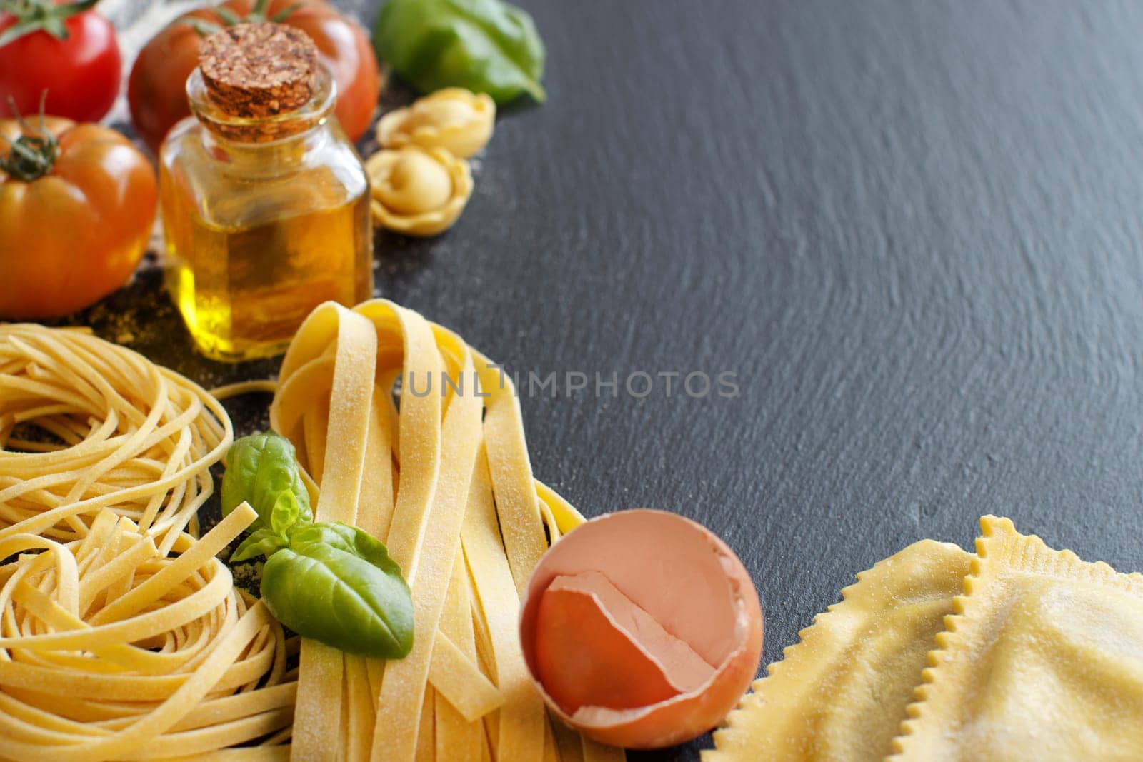 Fresh pasta and ingredients on a dark board close up