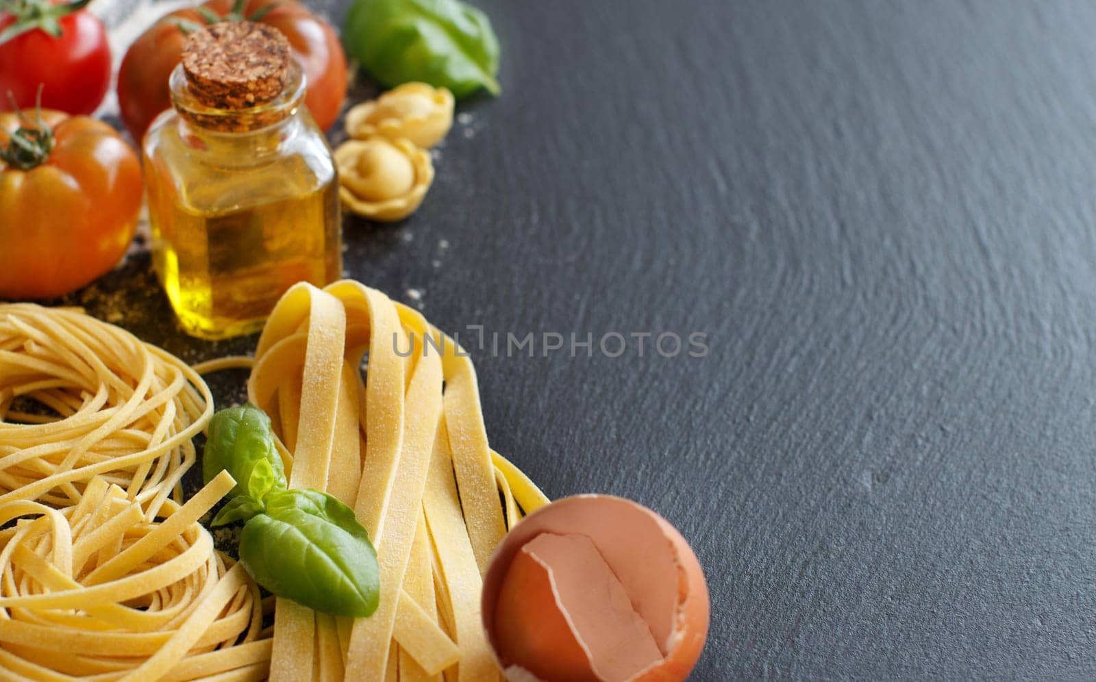 Fresh pasta and ingredients on a dark board