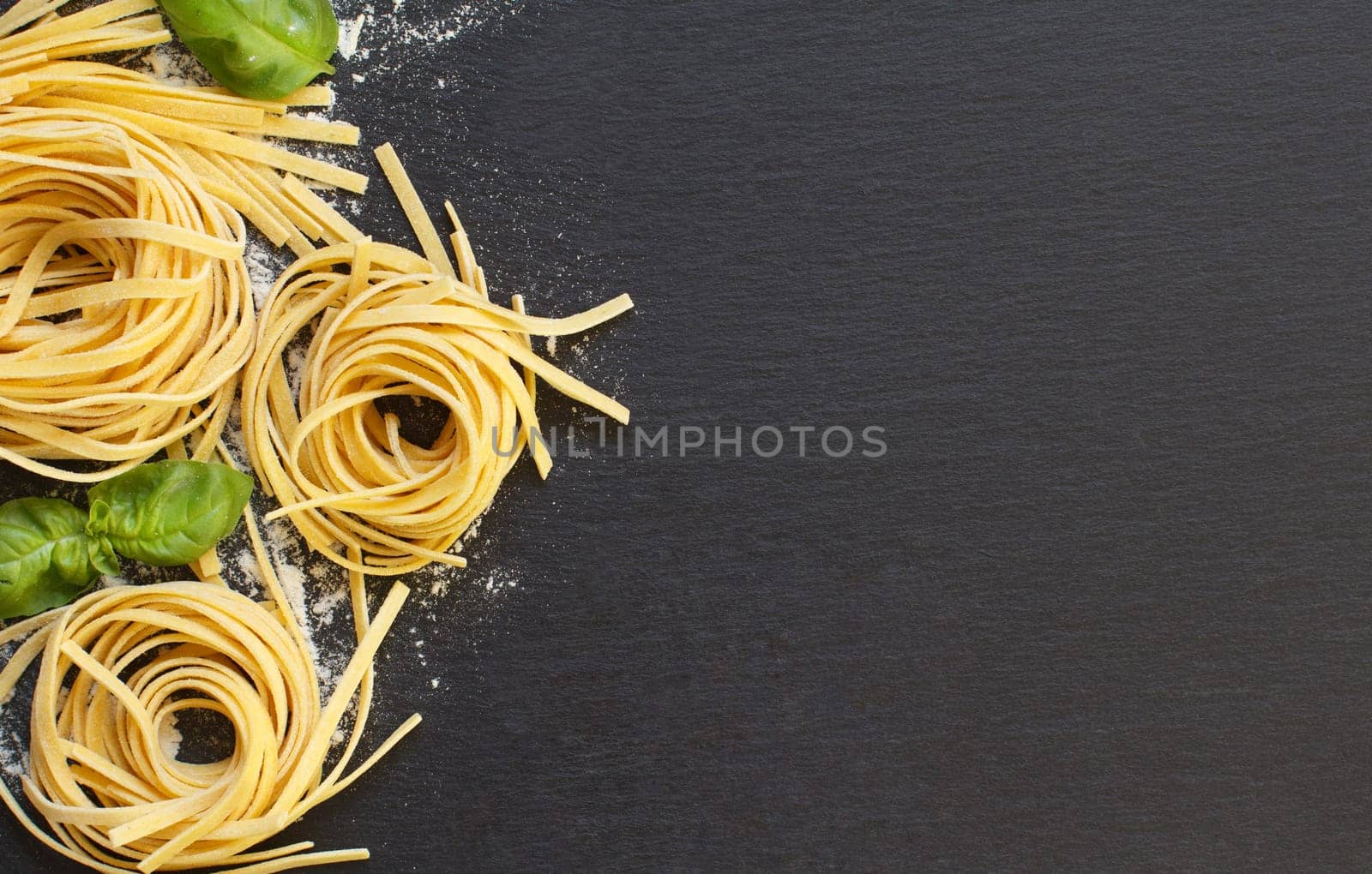 Fresh italian pasta and basil on a dark background