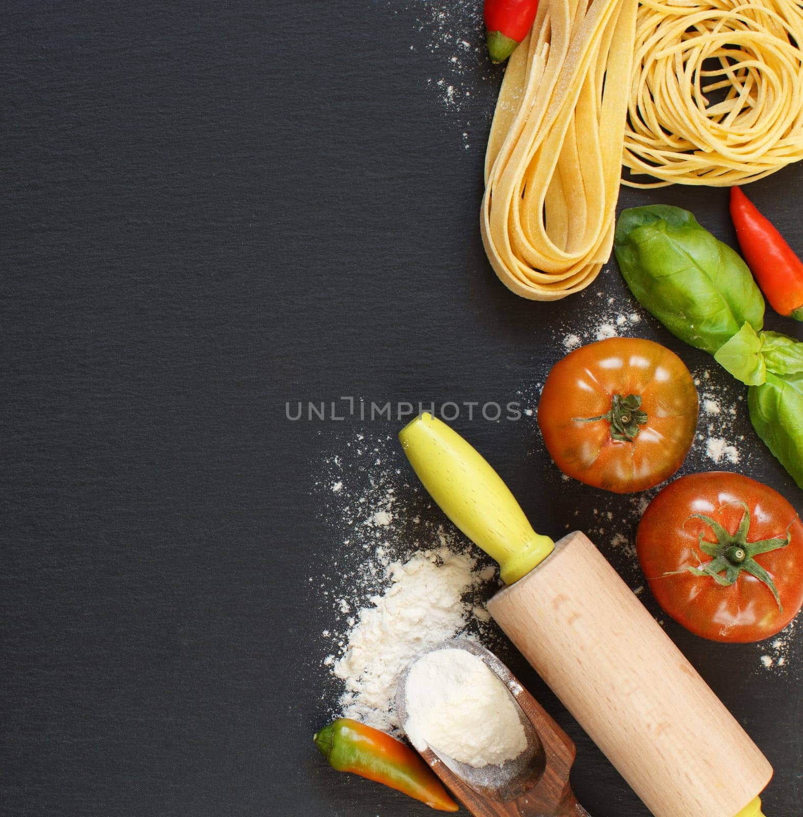 Fresh pasta and ingredients on a dark board top view