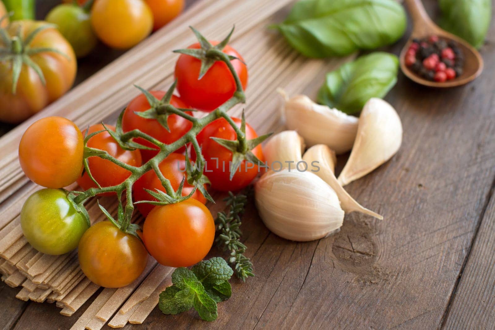 Raw fettuccine pasta, vegetables and herbs on wooden background