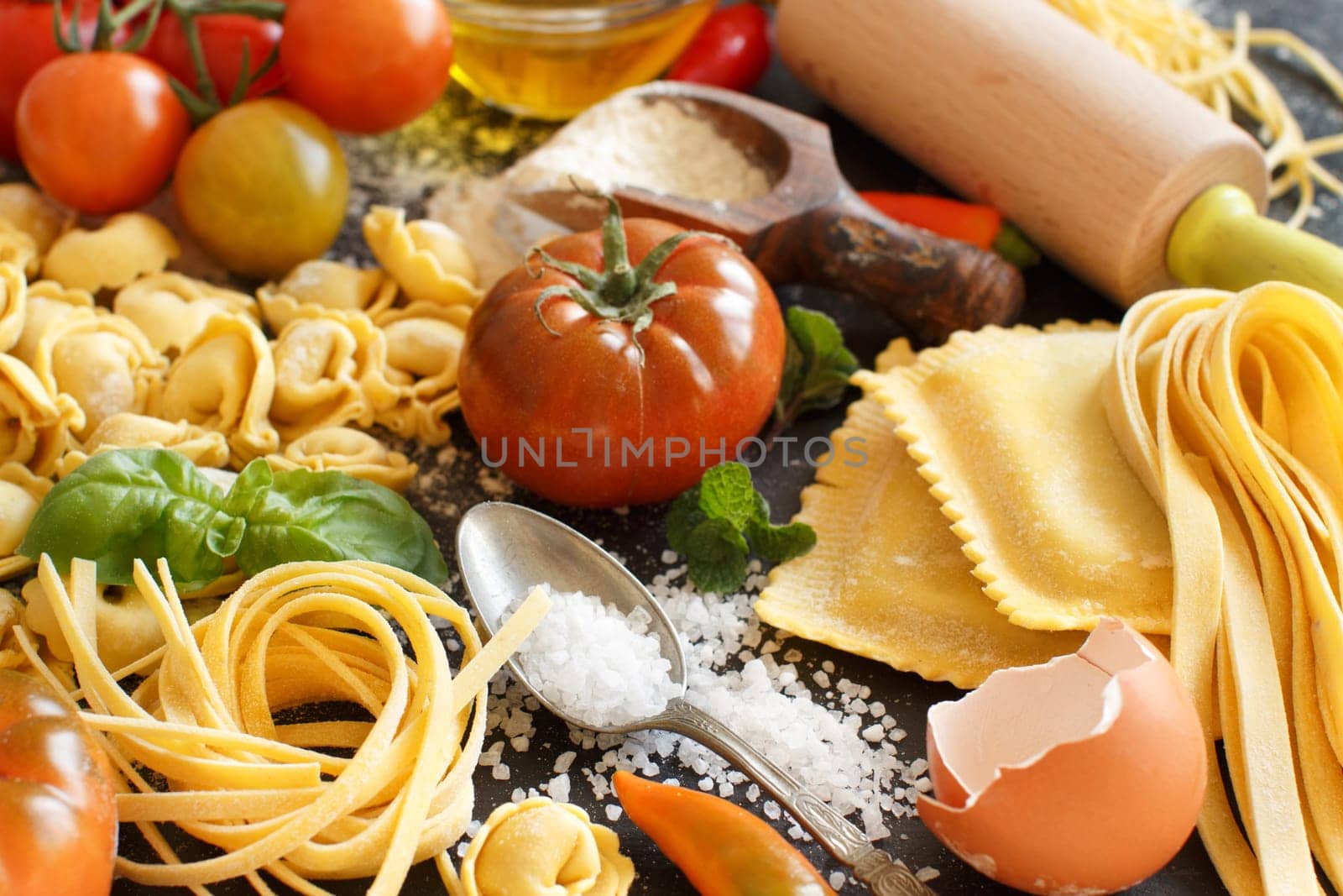 Fresh pasta and ingredients on a dark board close up