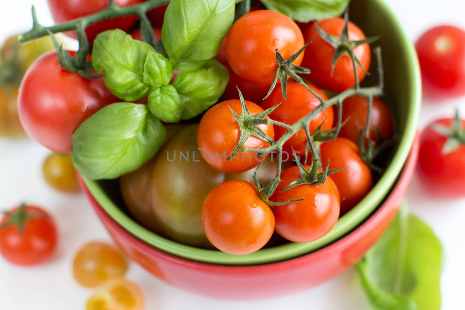 Cherry tomatoes and basil in bowl isolated on white background