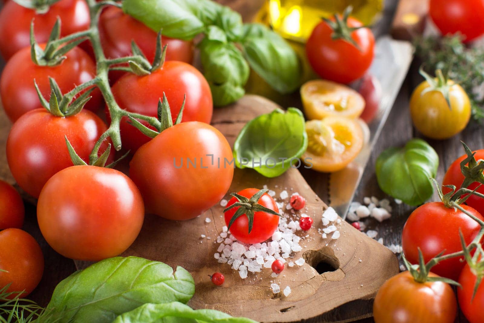 Cherry tomatoes, basil and olive oil on a wooden table
