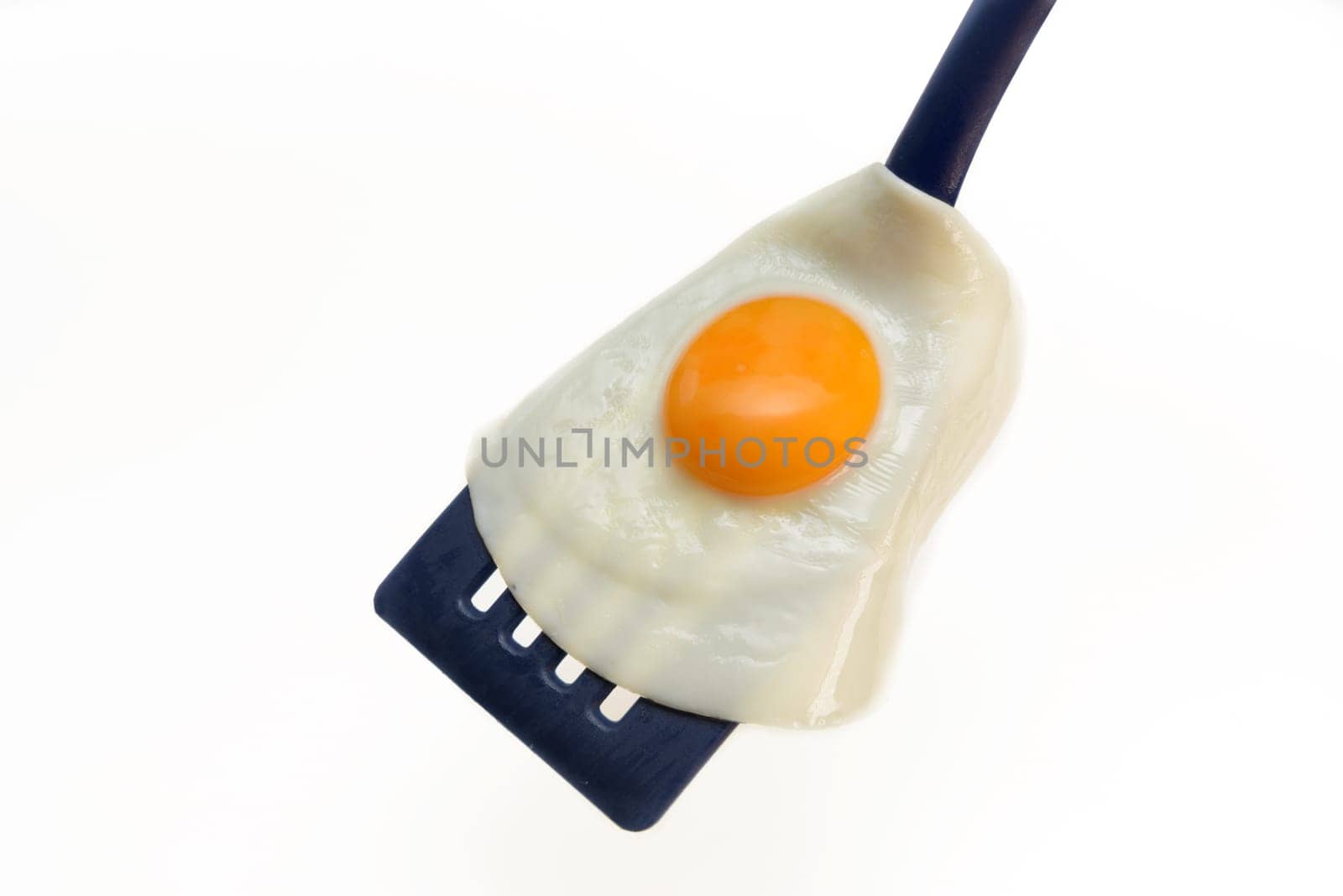 Fried egg on the spatula, ready to be served. White background.