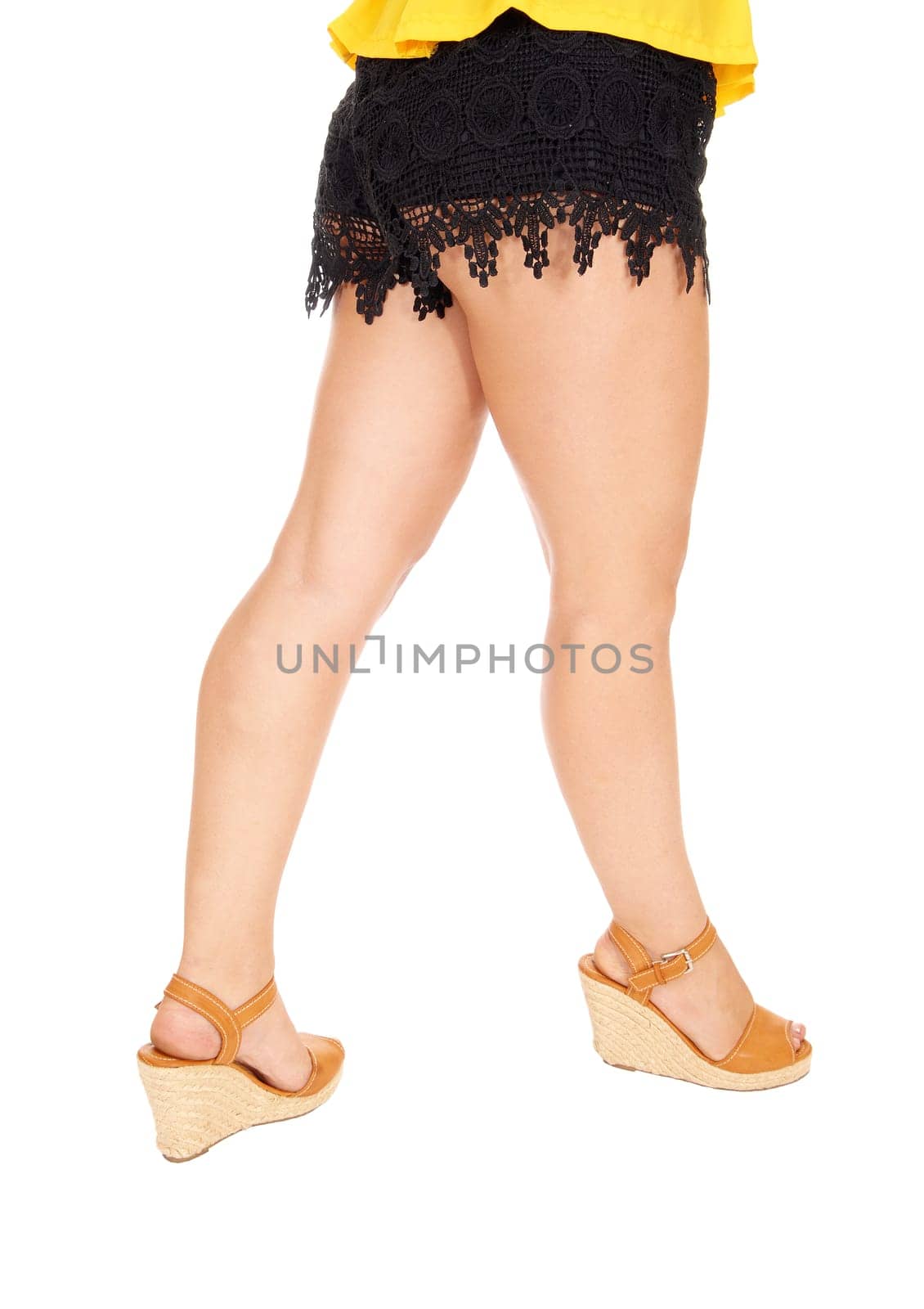 The legs of a young woman standing in high heels and black shorts,.isolated for white background..