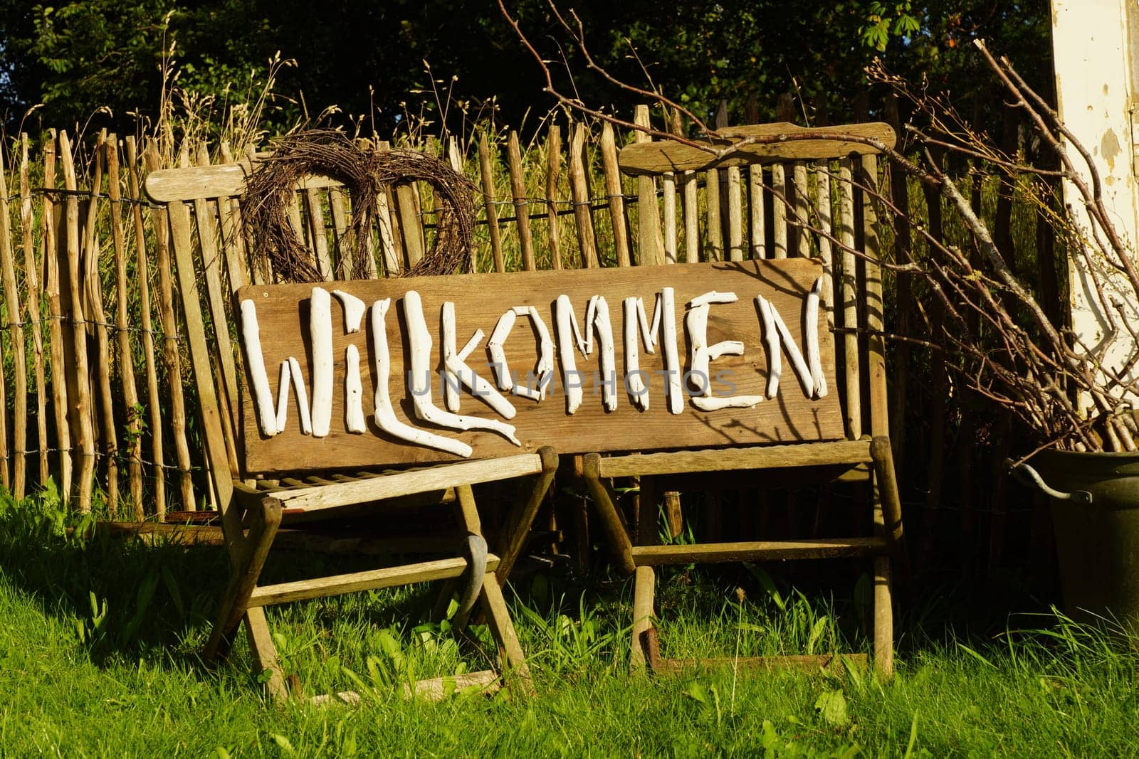 Two chairs in front of a farmhouse with a welcome sign