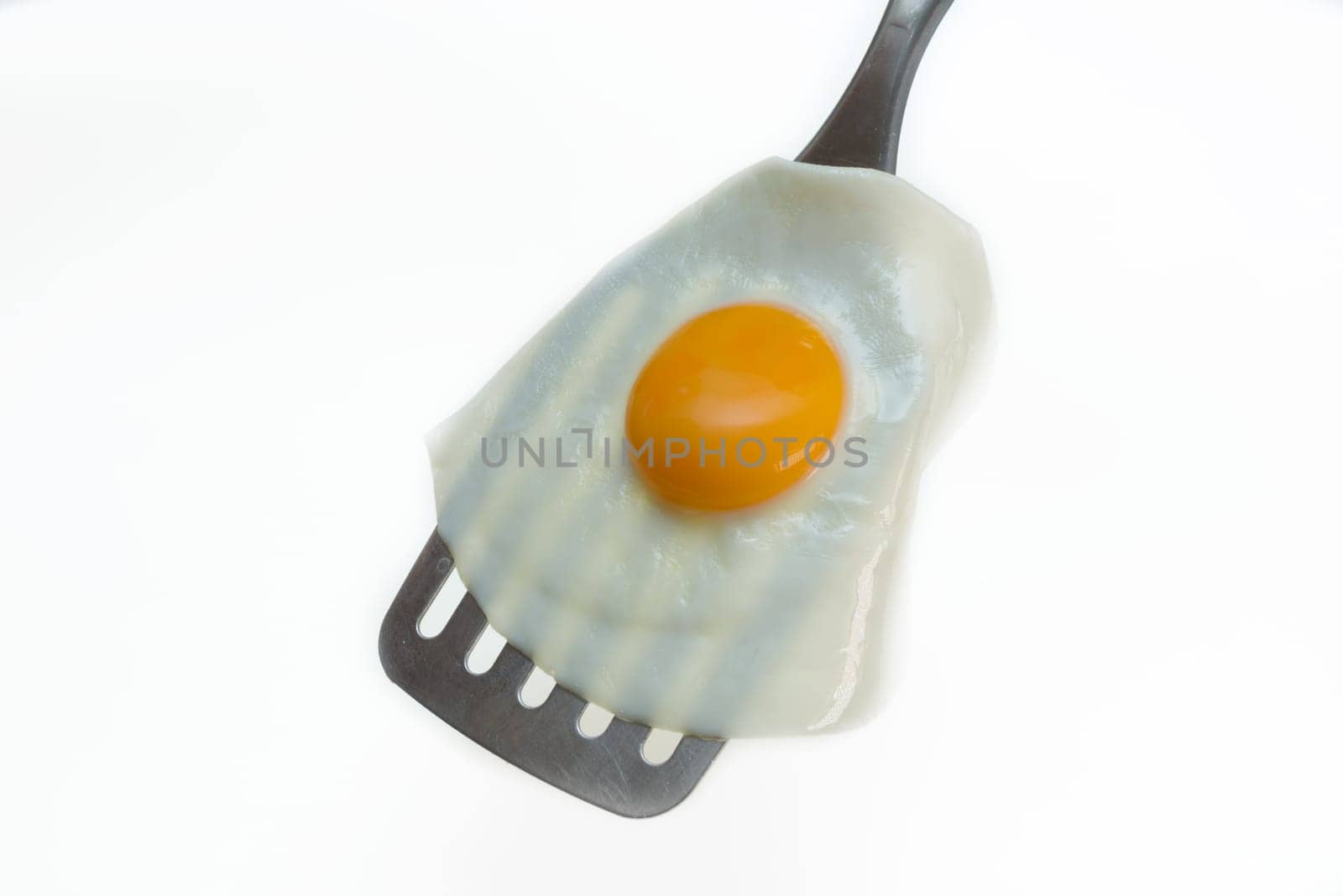 Fried egg on the spatula, ready to be served. White background.