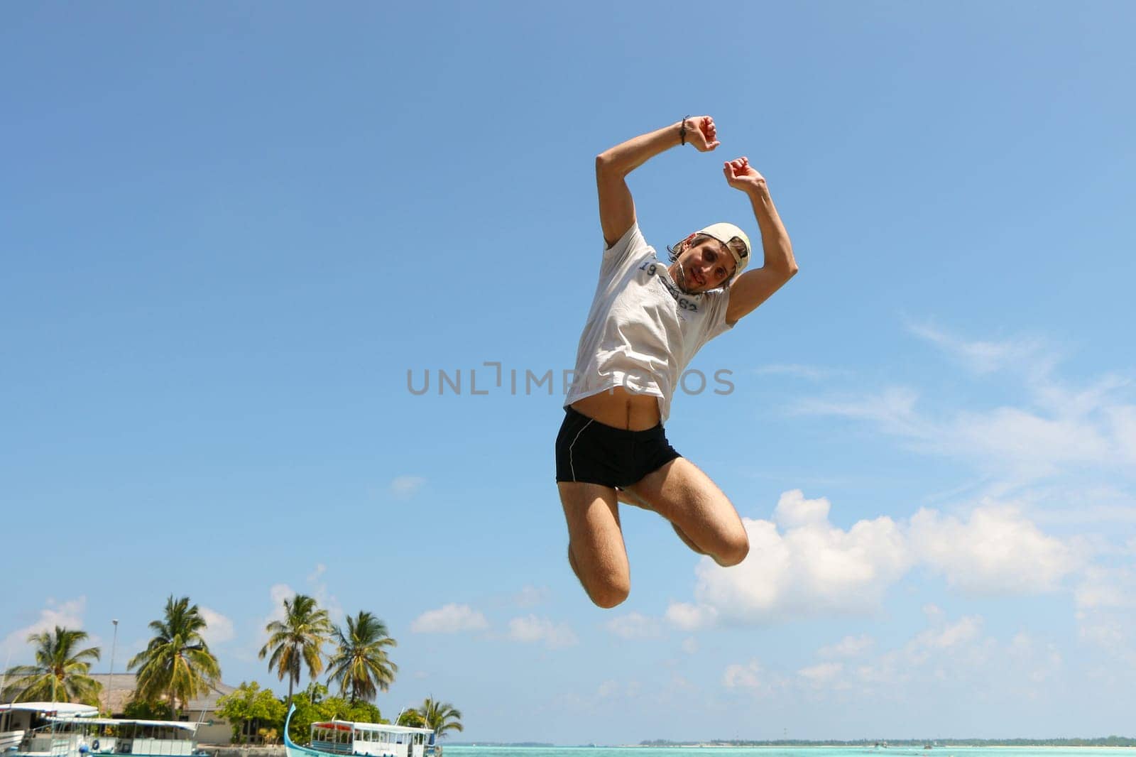 an jumping happy in the beach with a blue sky and palms in the background