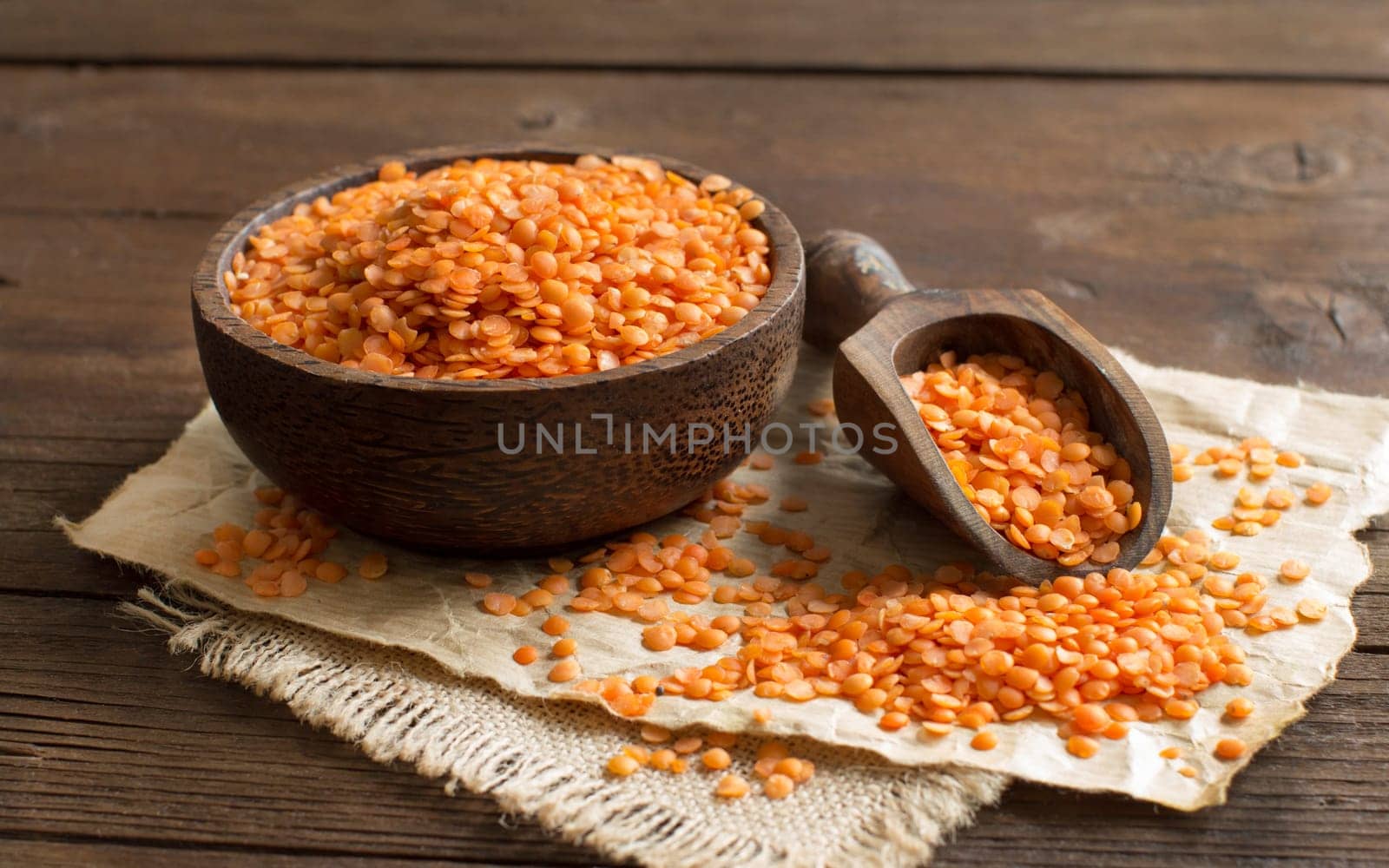 Red lentils in a bowl with a spoon on a wooden table