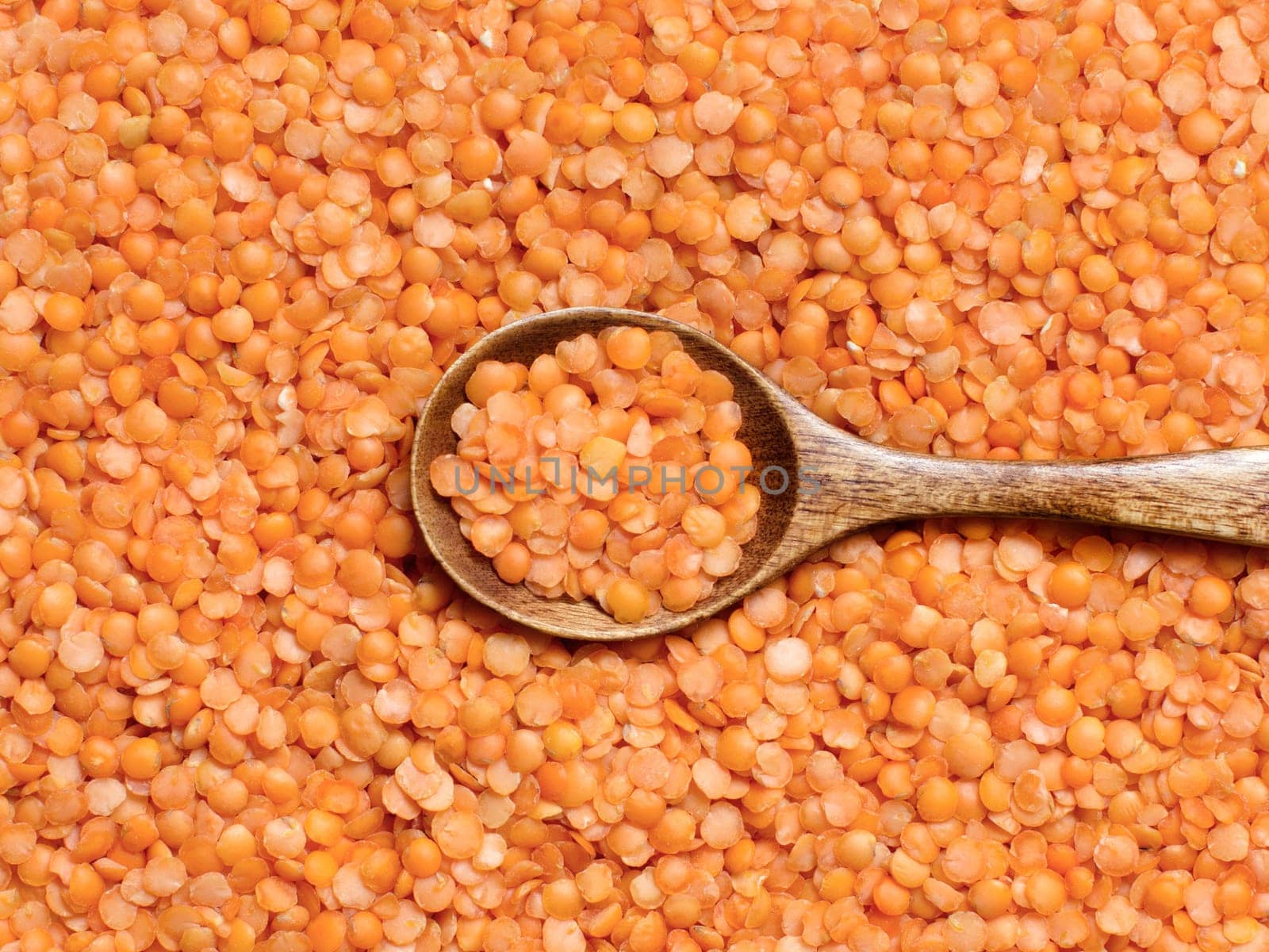 Red lentils with a spoon close up top view
