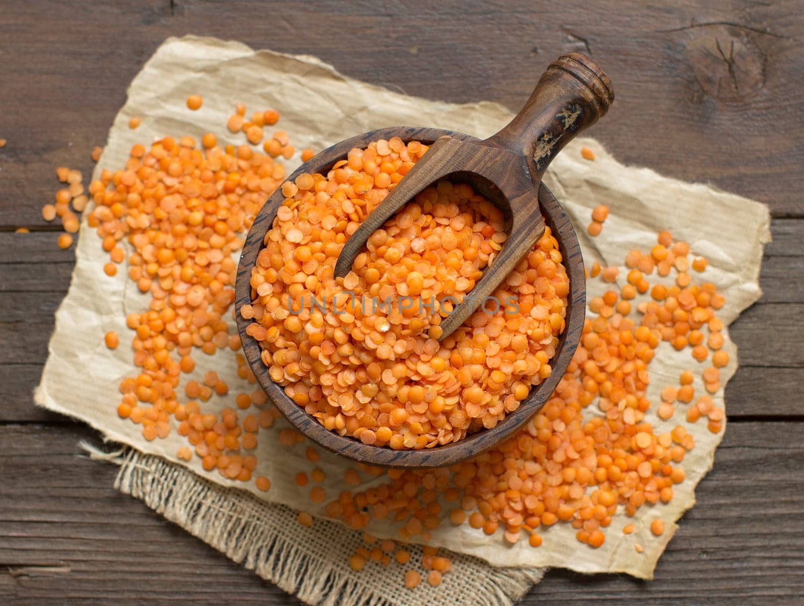 Red lentils in a bowl with a spoon on a wooden table