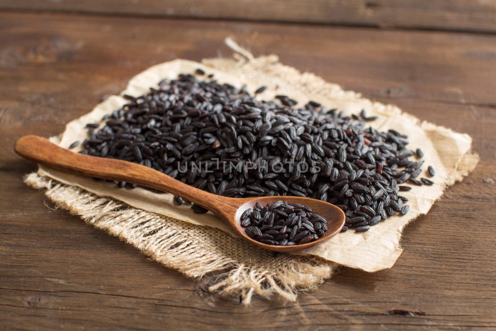 Pile of black rice with a spoon on a wooden table